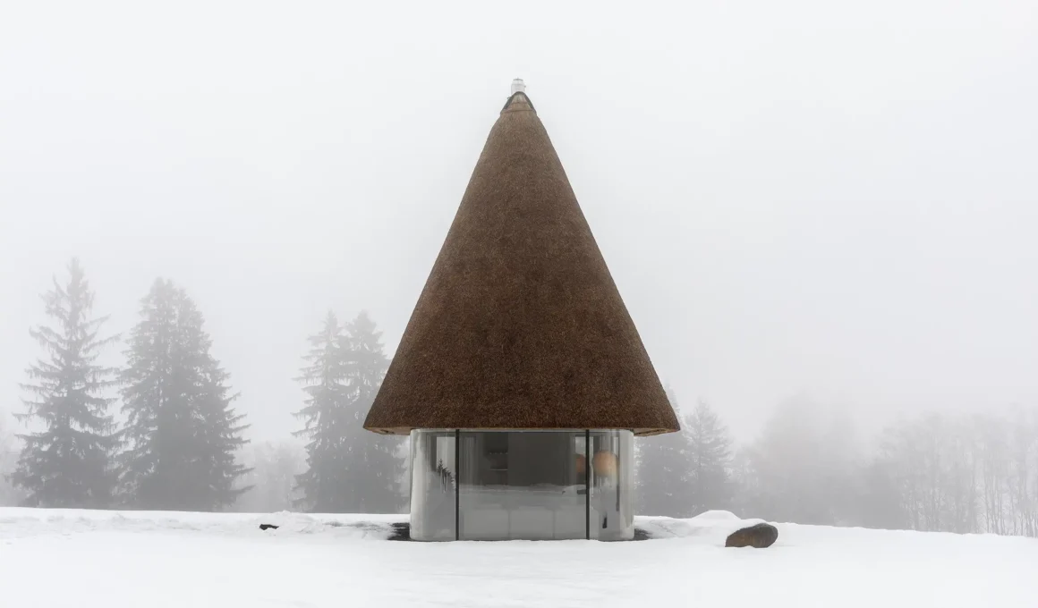 A tall, conical reed roof guesthouse standing in a snowy field in Ukraine.