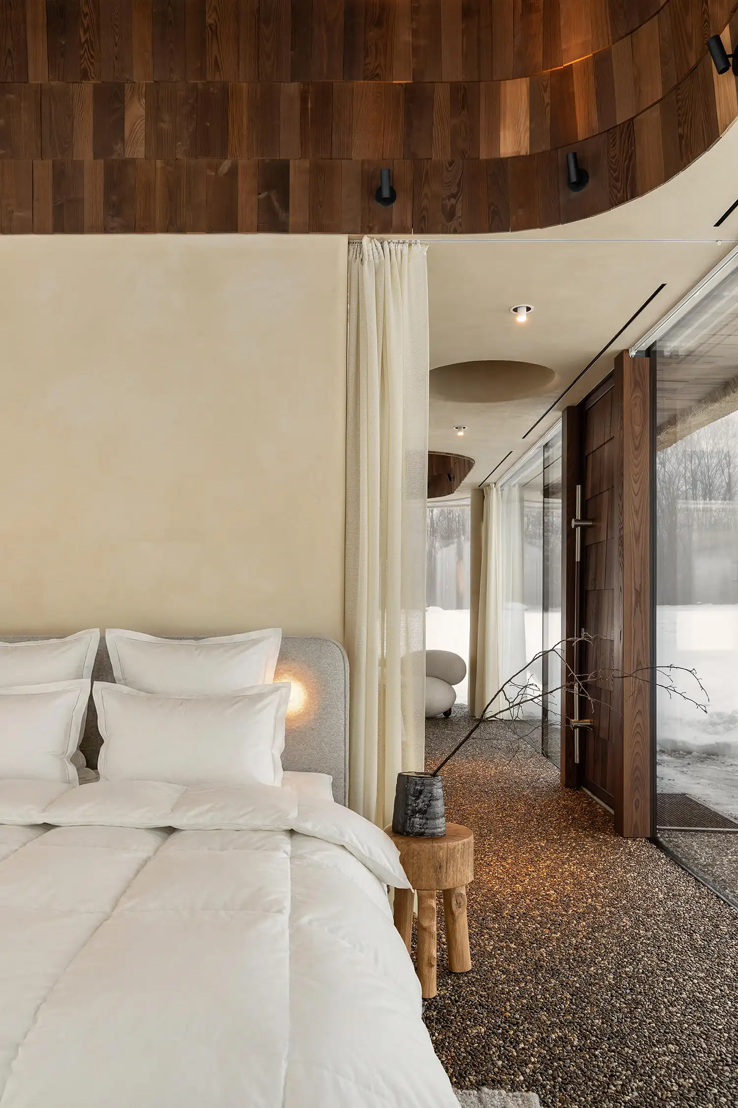 Minimalist bedroom with a view of the pebble floor and snowy exterior.
