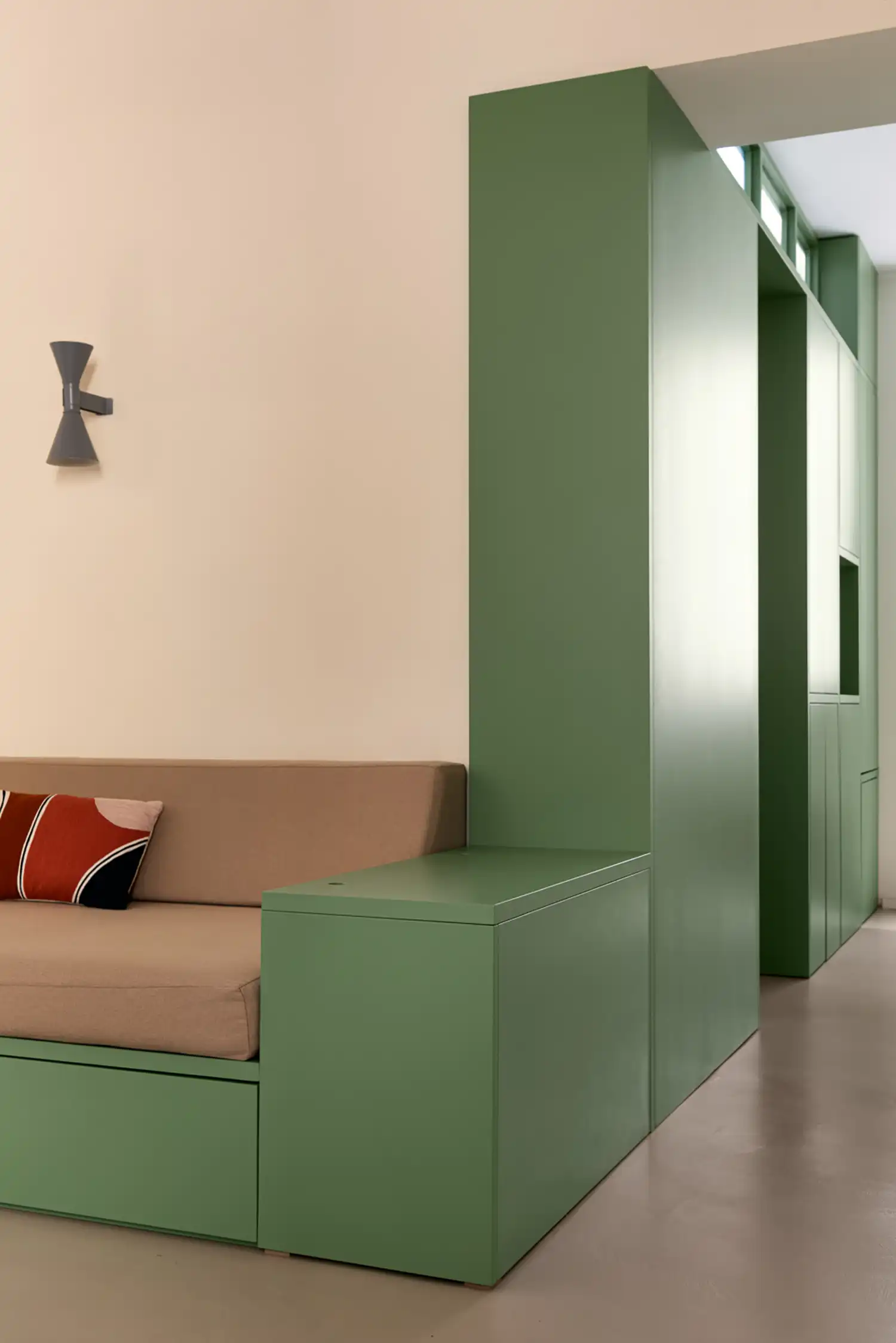 Detail of green floor-to-ceiling storage cabinetry next to a lounge area.