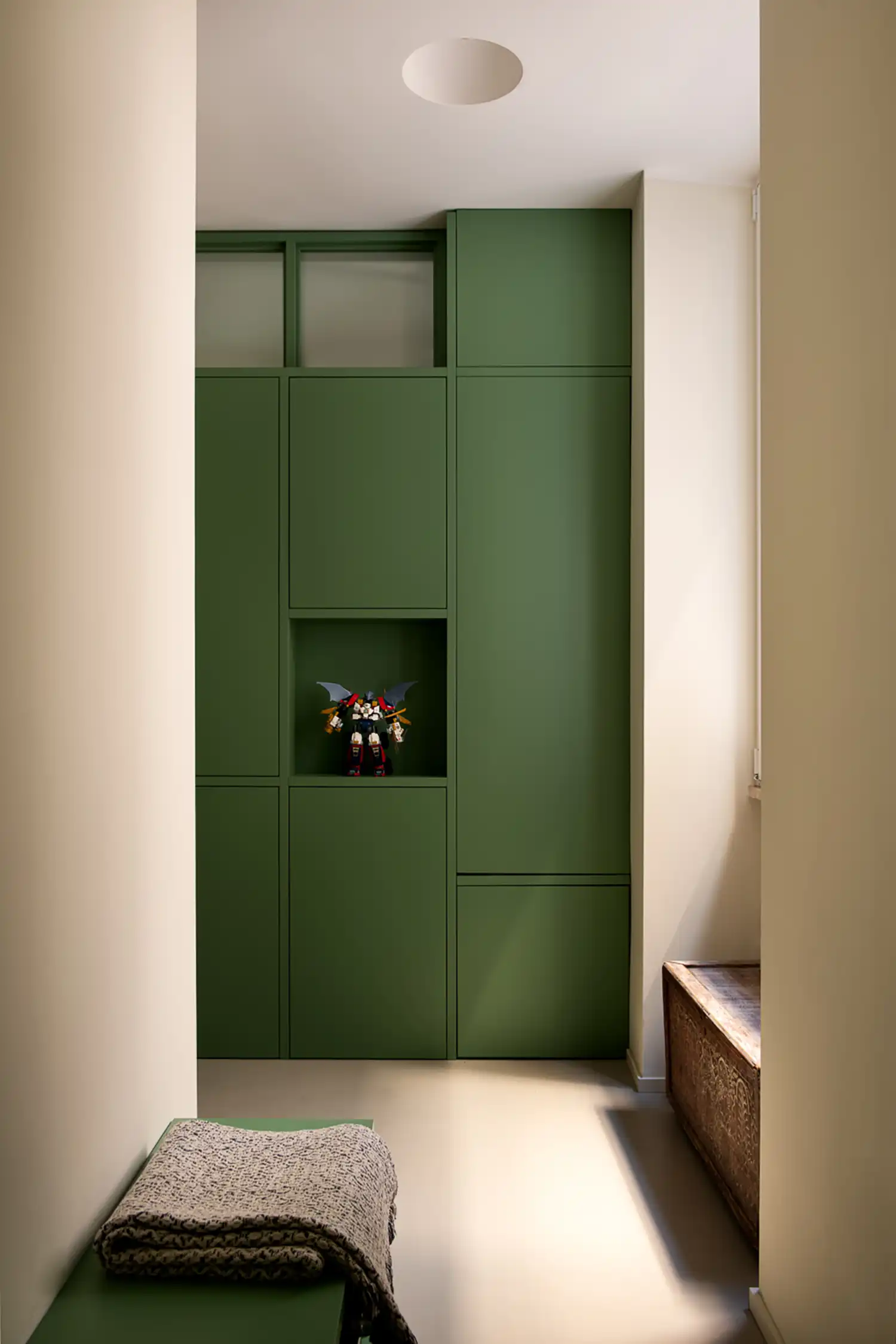 Hallway storage wall in green with a recessed niche displaying a robot toy.