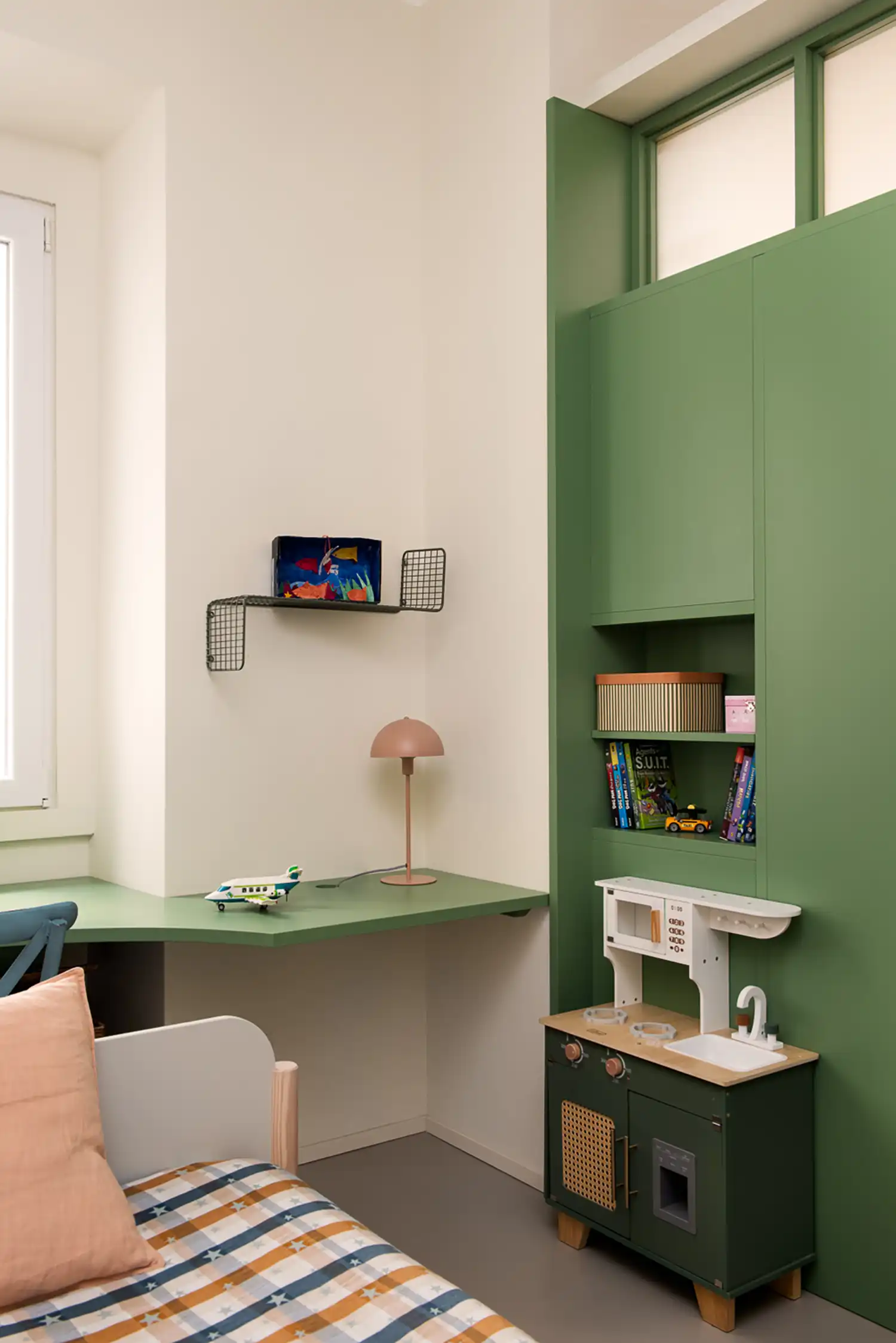 Children's room with a green corner desk and integrated shelving unit.