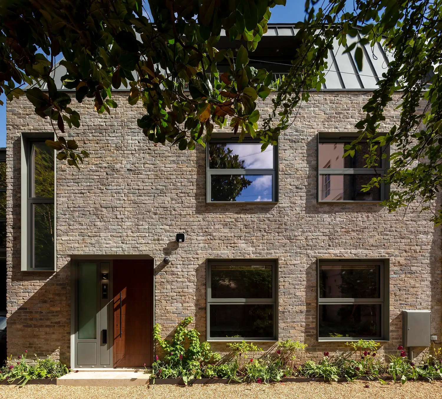 Front facade of Archi-Tectonics' London Solar House featuring a wooden door and large windows.