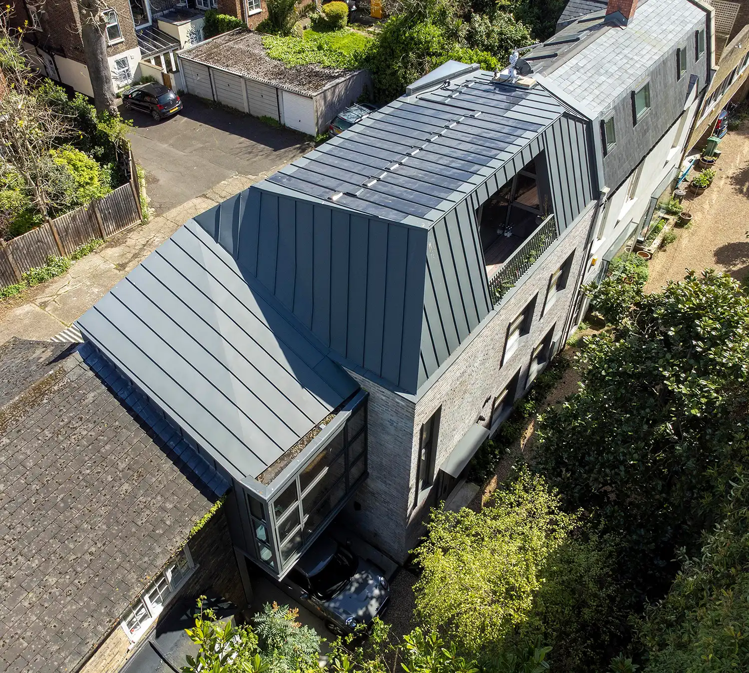 Aerial view of a faceted zinc roof with integrated solar panels on a London terrace.