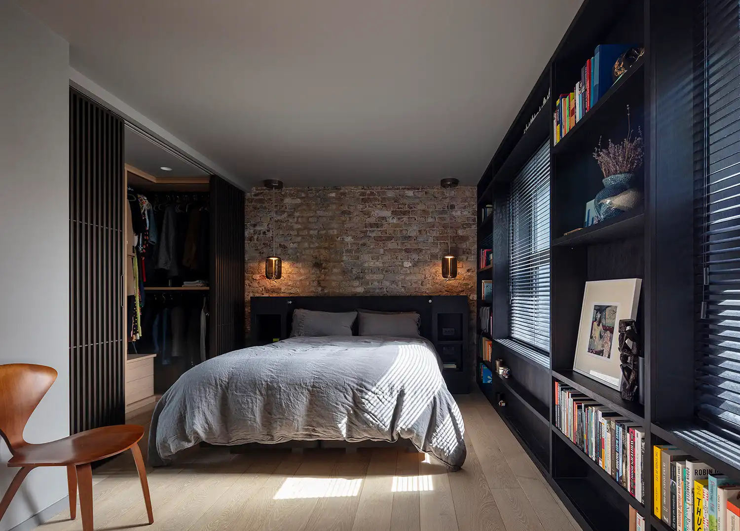 Modern bedroom with exposed brick, black cabinetry, and a walk-in closet.