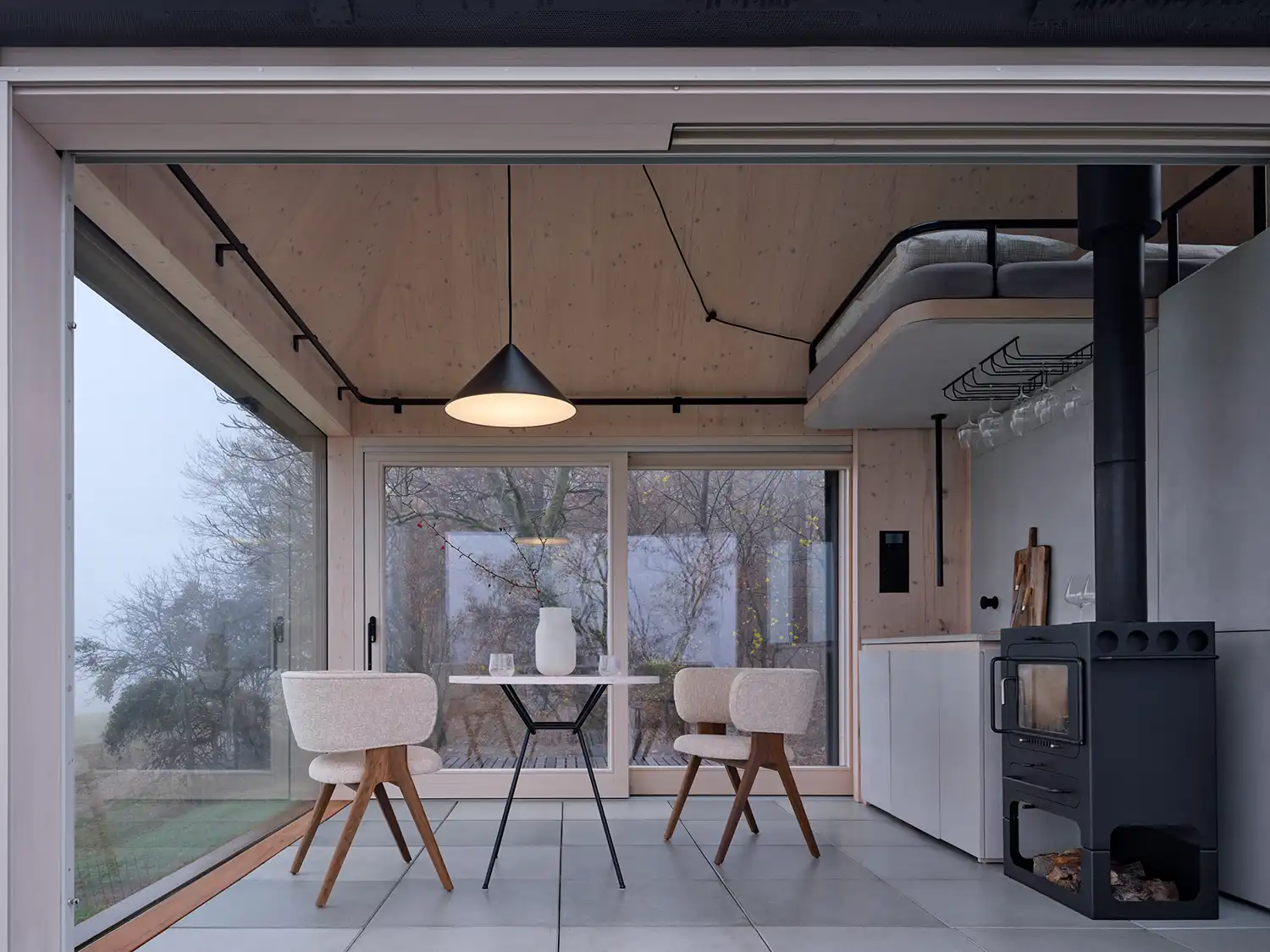 Minimalist interior of Cabin Devín featuring light wood and a black fireplace.