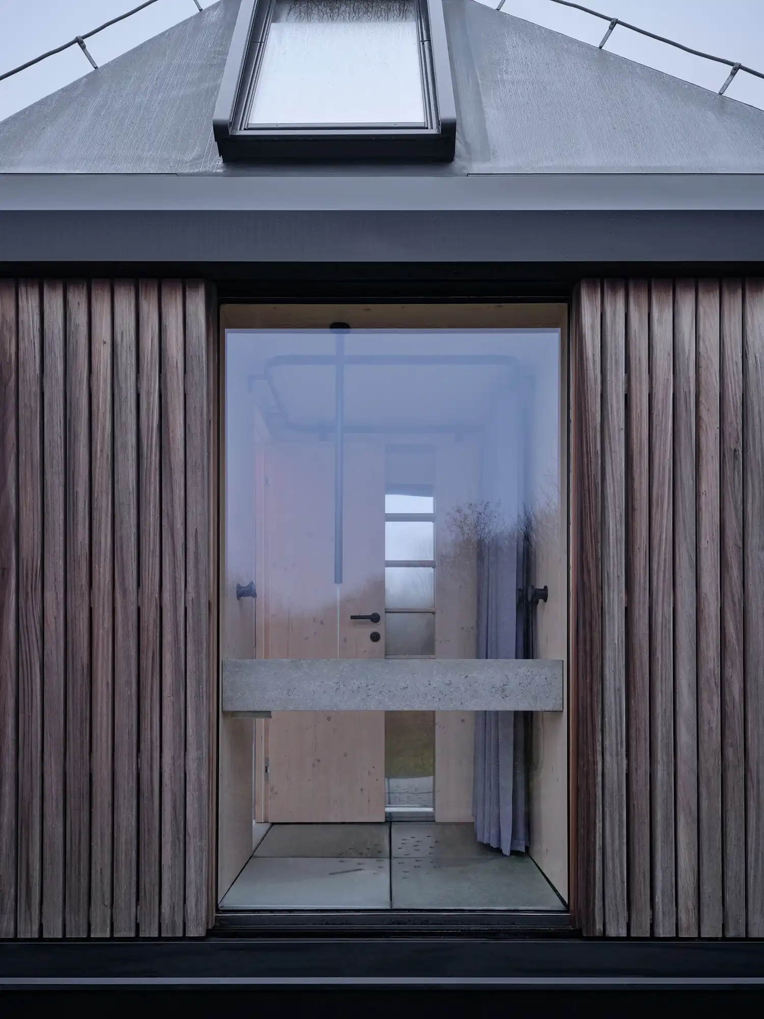 Detail of the cabin's exterior wood cladding and glass entry.