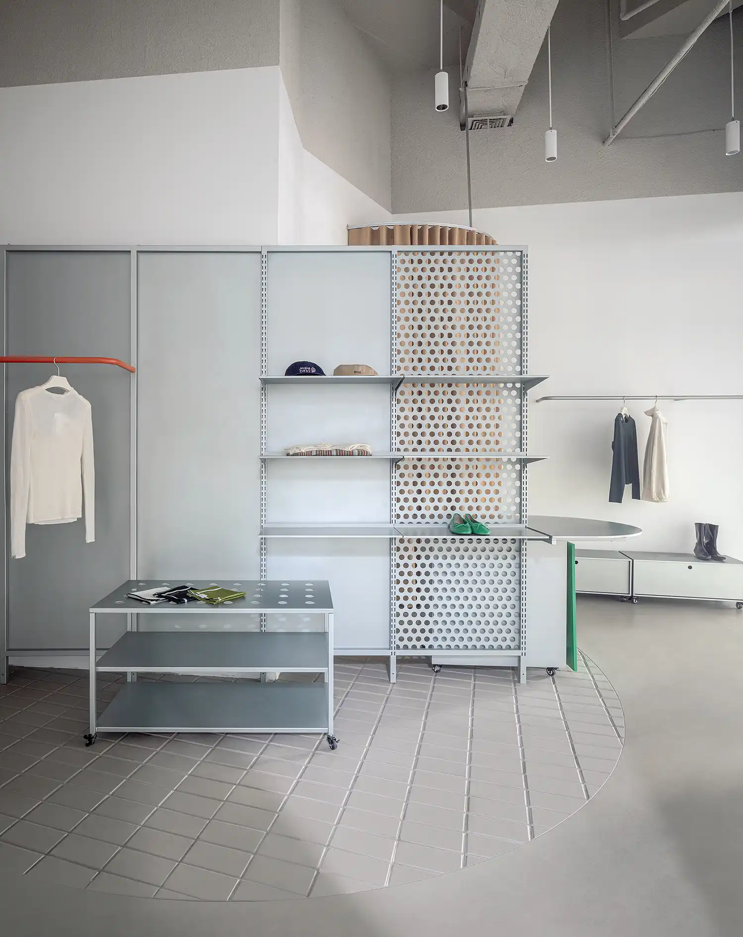 Interior shot of modular grey shelving units, a bright green counter, and circular tiled floor patterns.