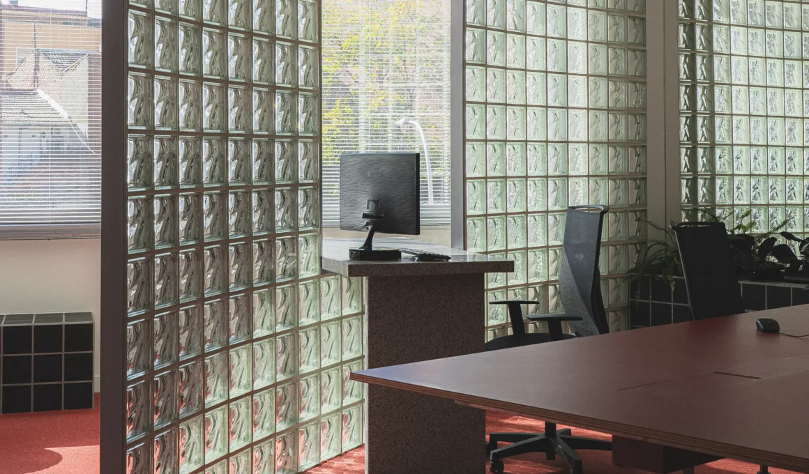 A granite desk integrated into a glass-block wall partition with a red carpet floor.