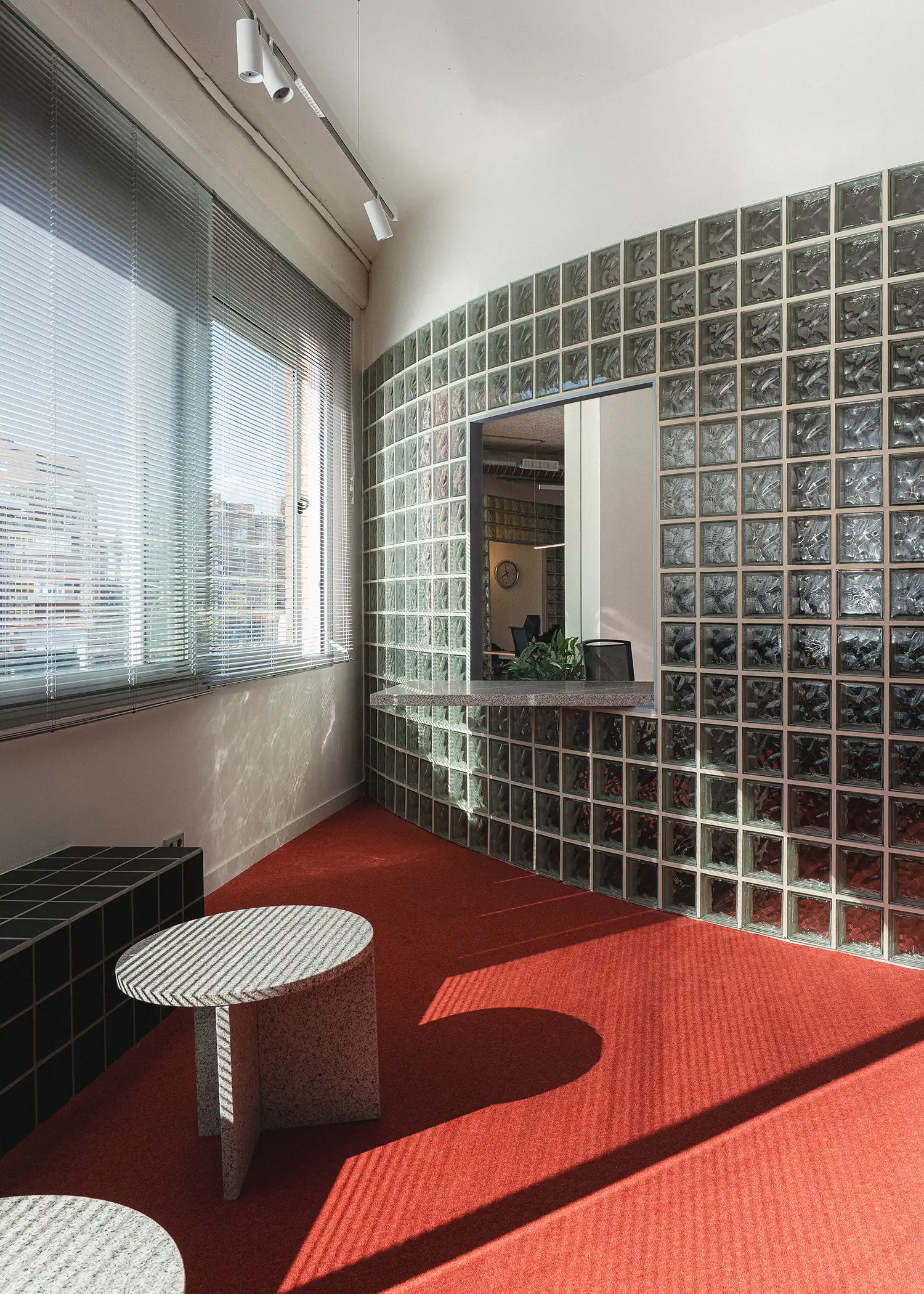 Curved glass-block wall with a granite service ledge overlooking a red-carpeted office area.