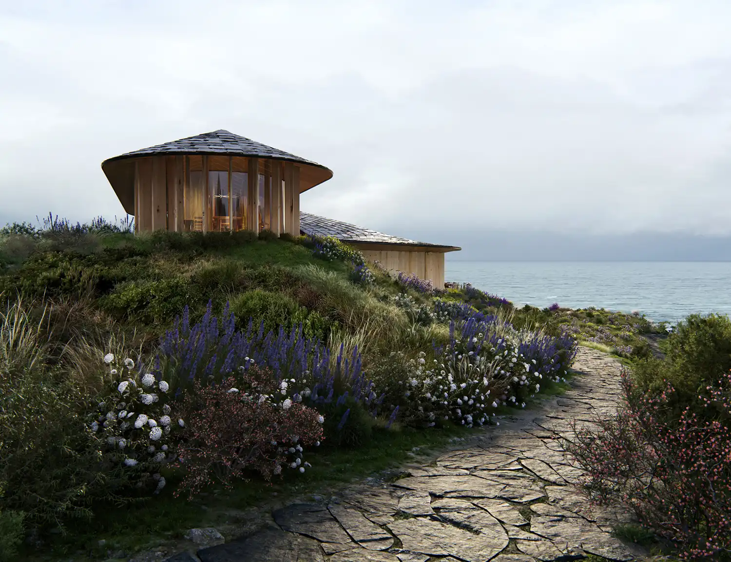 A low-angle view from a cobblestone path looking up at a circular, timber-framed pavilion on a hill. Purple flowers and wild grasses surround it under a cloudy sky.