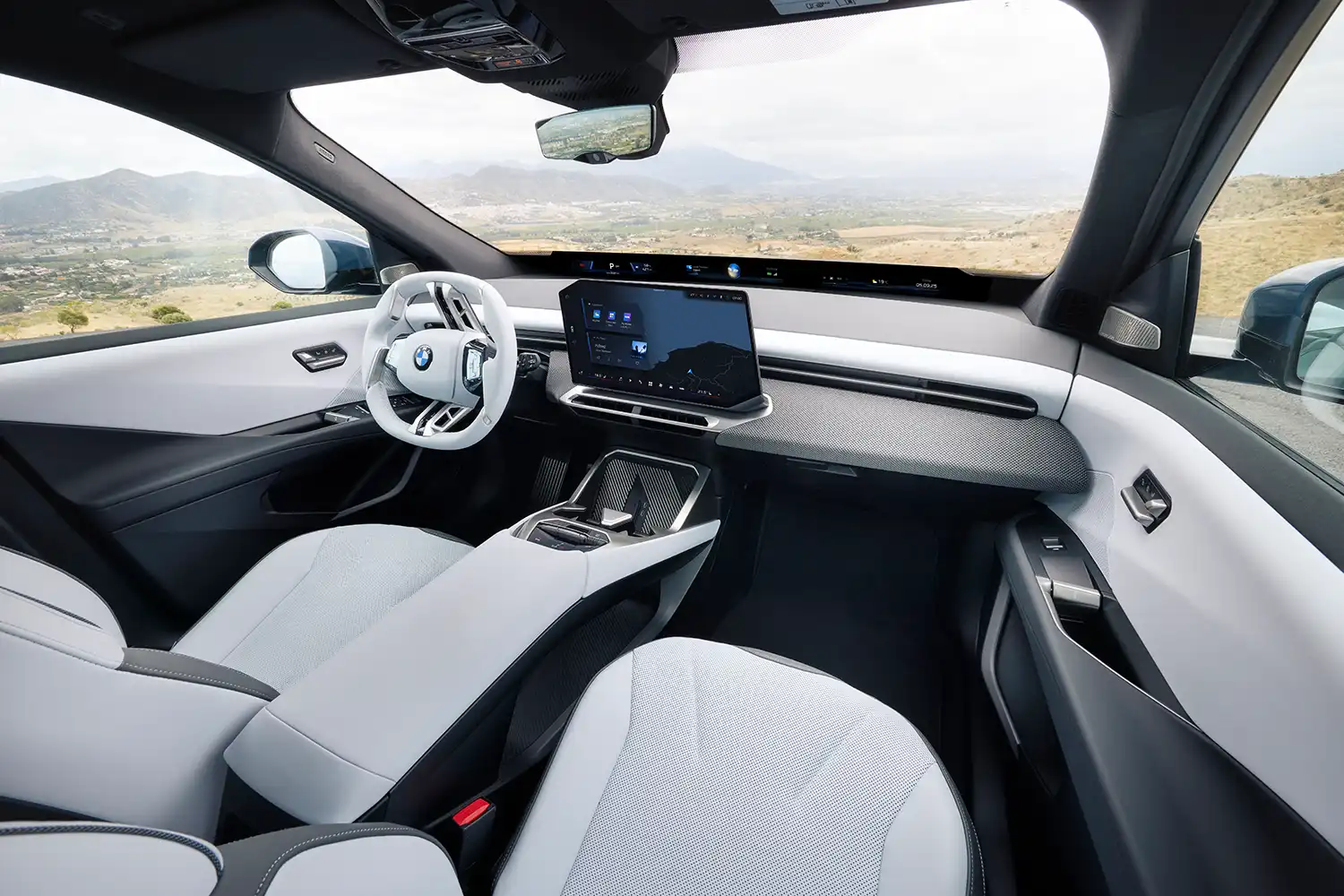Wide interior shot of the 2026 BMW iX3 showing sustainable textile upholstery and minimalist cabin.