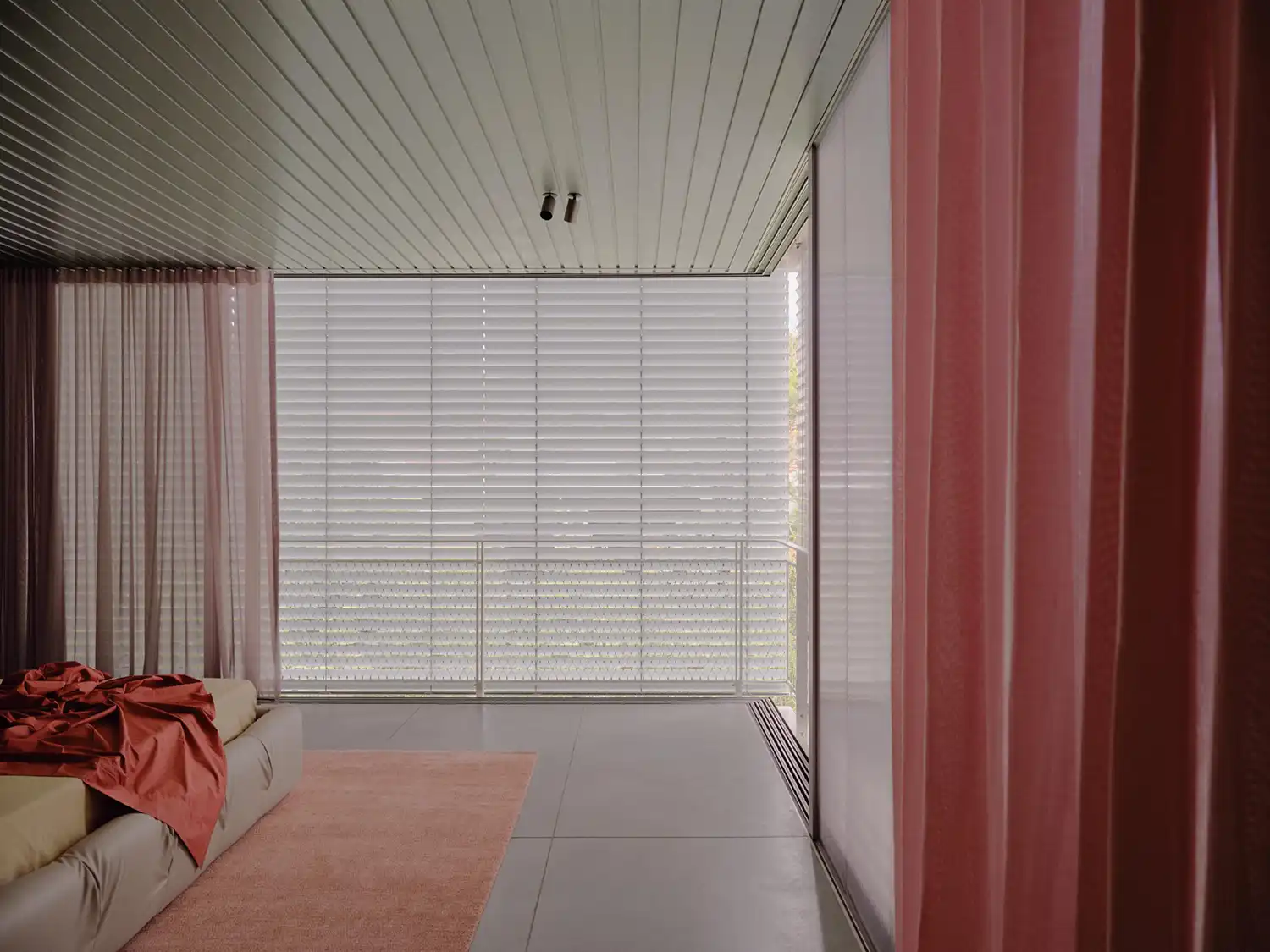 Modern bedroom with a low-profile bed, pink curtains, and adjustable white aluminum louvres.
