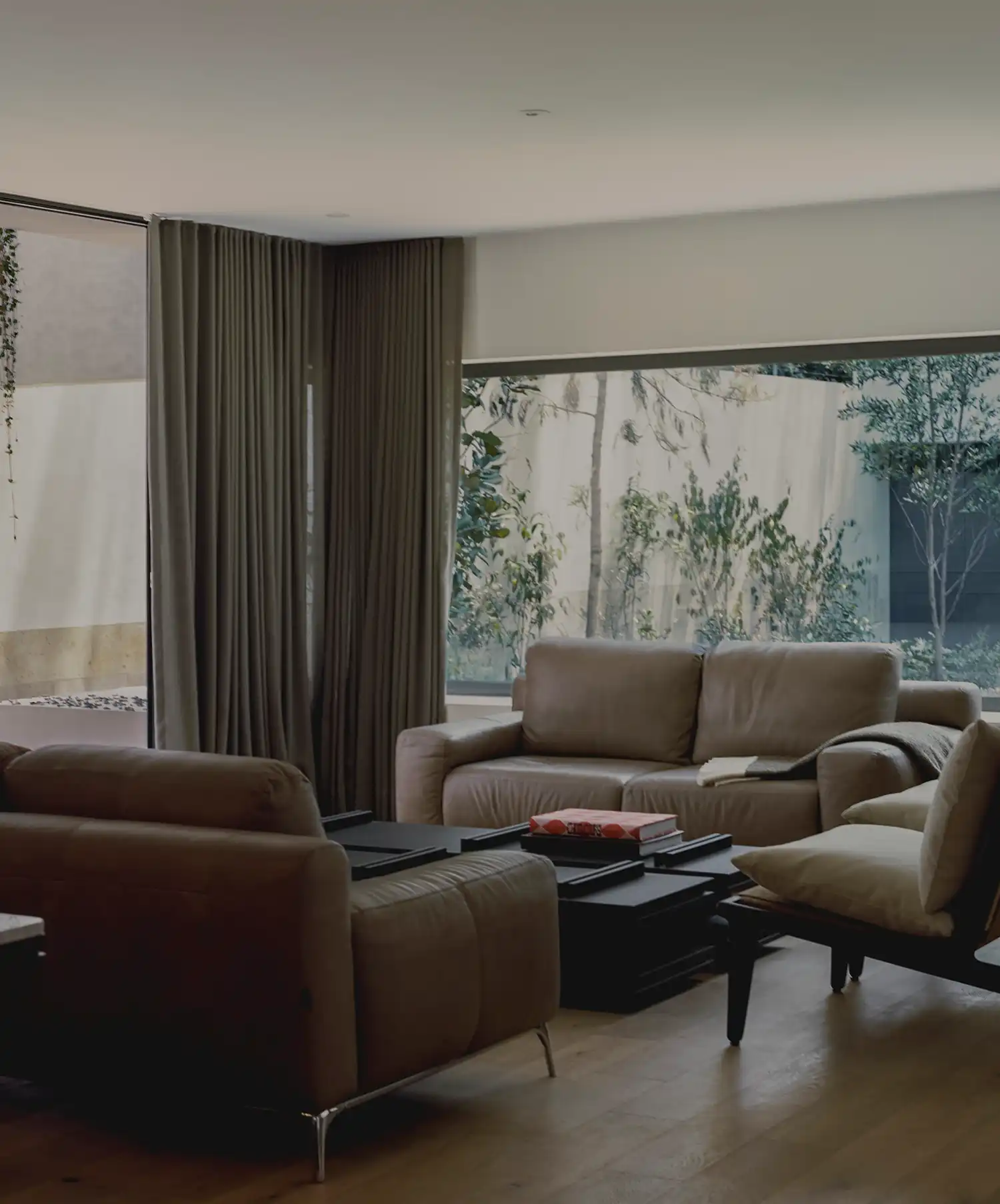 Contemporary living room with brown leather sofas and a large window overlooking a garden.
