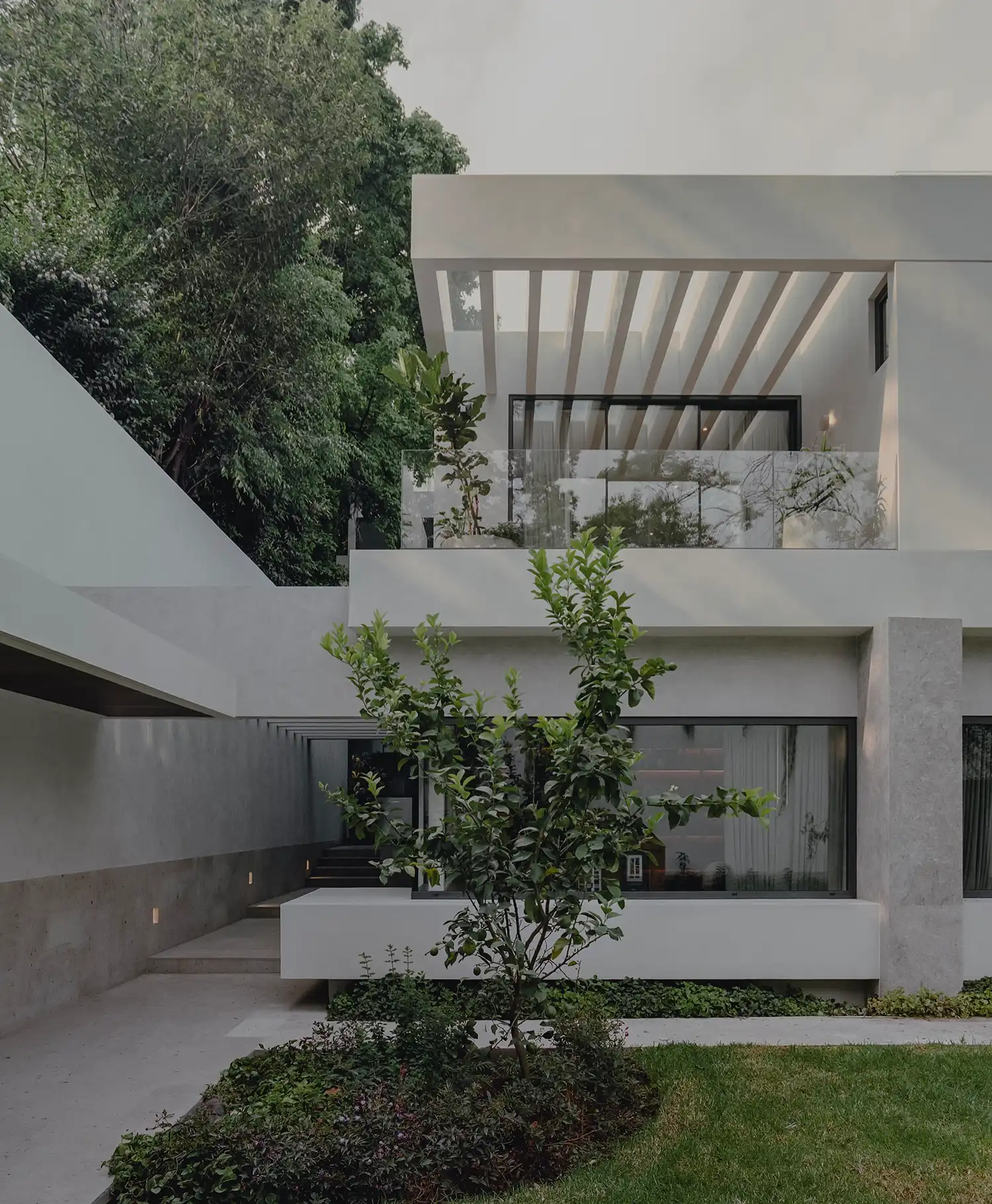Full facade view of the CDLA House renovation showing stacked white volumes and a central garden tree.