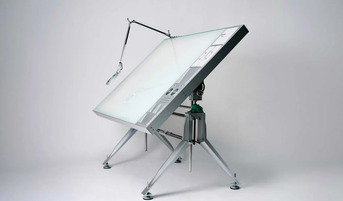 Profile view of Caliper's aluminium drafting table tilted at an angle with a magnifying lamp.