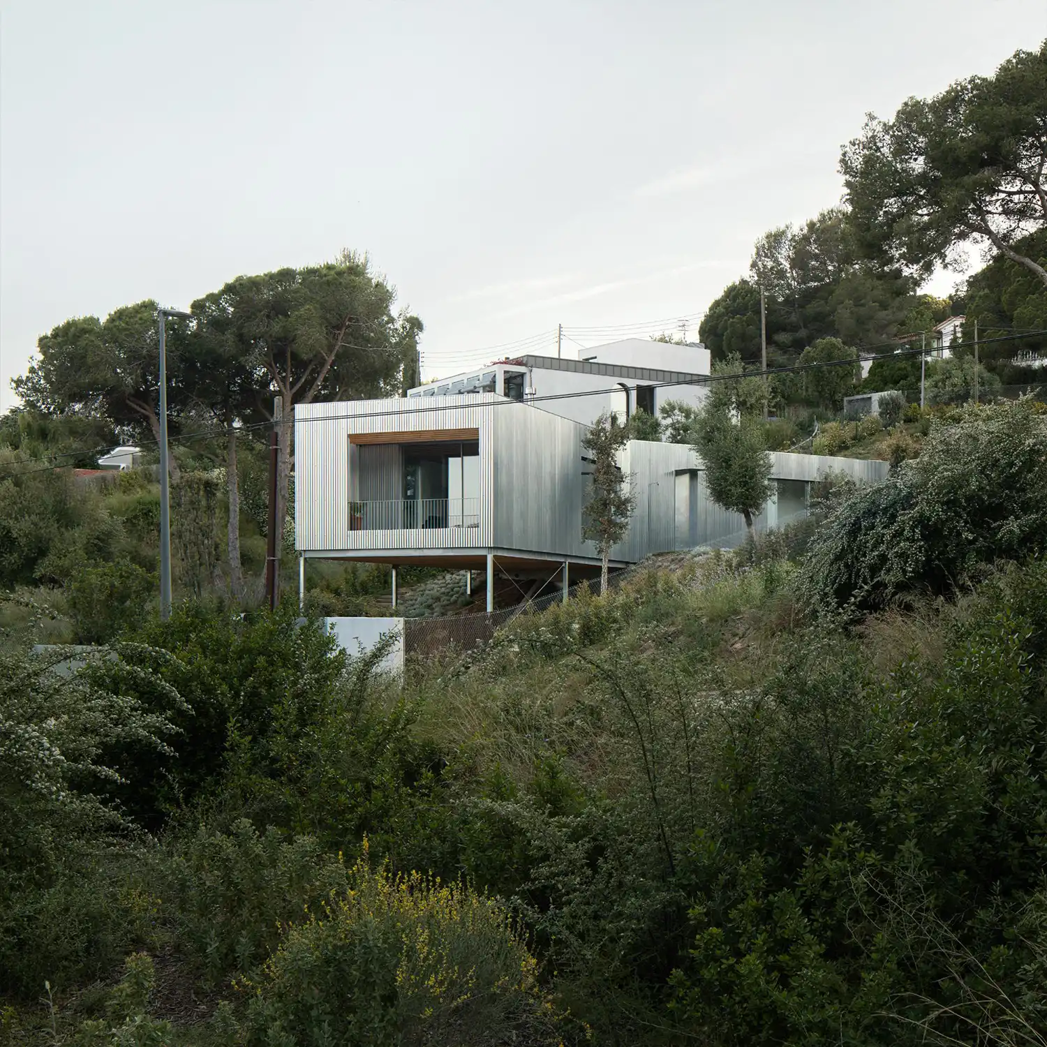 A side view of the metallic house showing its "broken" 144-degree geometry and cantilevered end over the hill.