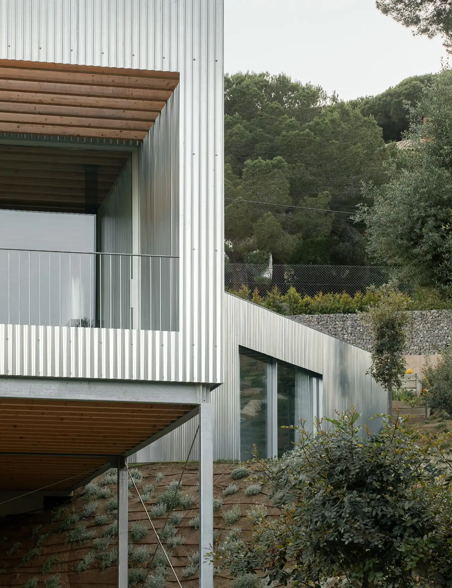 Close-up of the steel facade and a sheltered terrace with exposed timber ceiling beams.