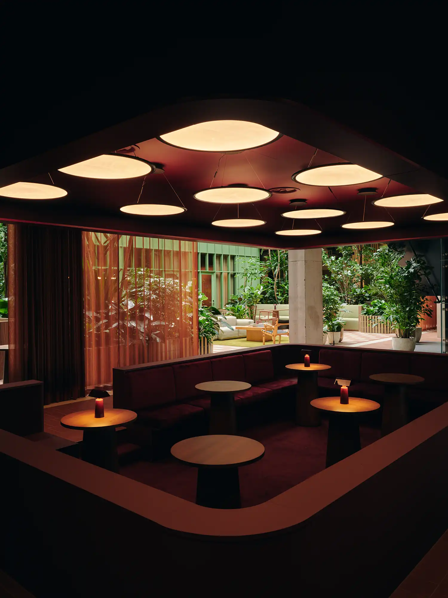 A sunken conversation pit with deep red velvet upholstery and a low acoustic ceiling.