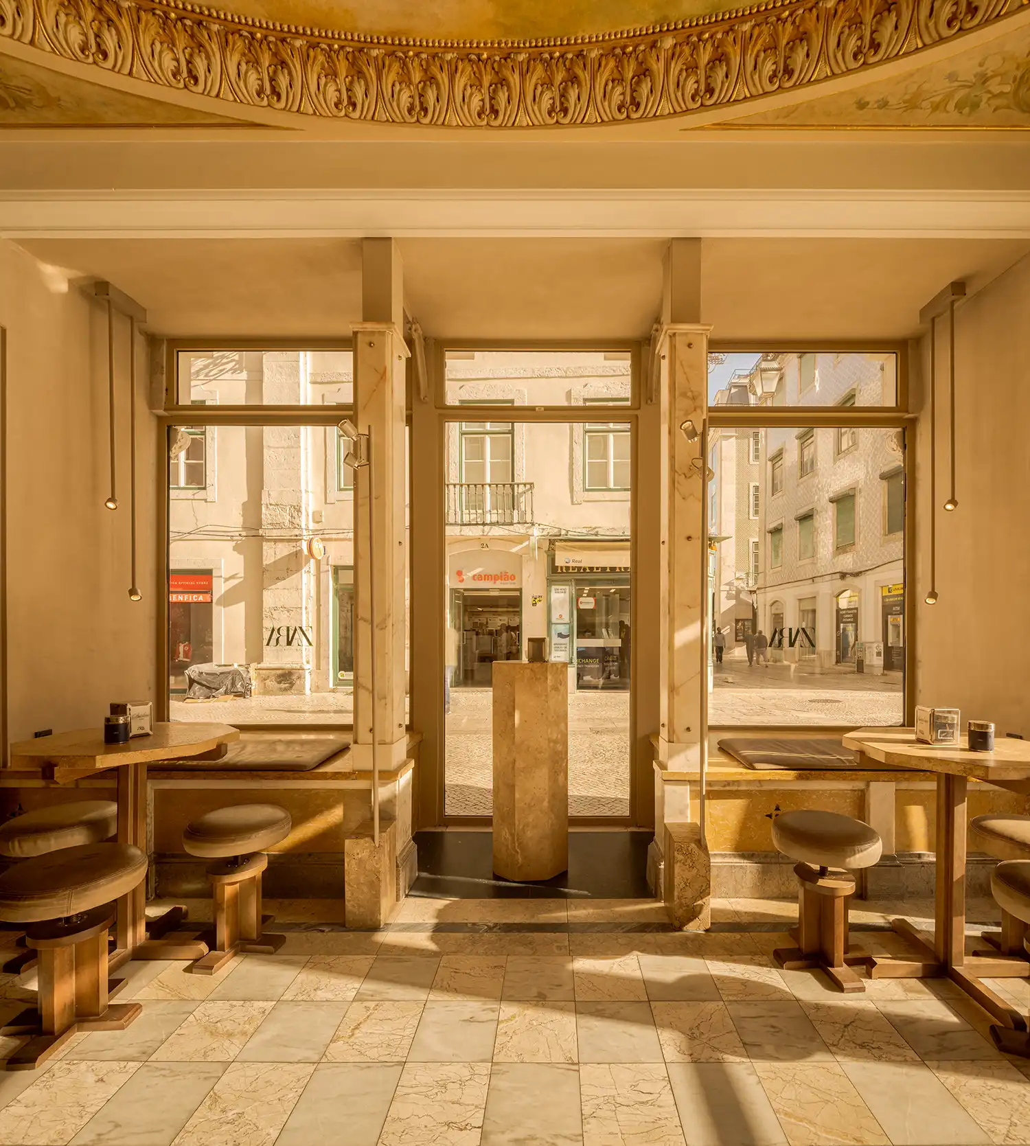 Interior of a café with marble floors and large windows facing the Lisbon streetscape