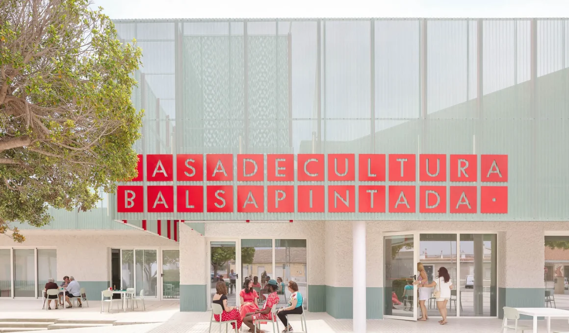 Exterior view of Balsapintada Cultural Center in Murcia featuring a perforated metal facade and red signage.