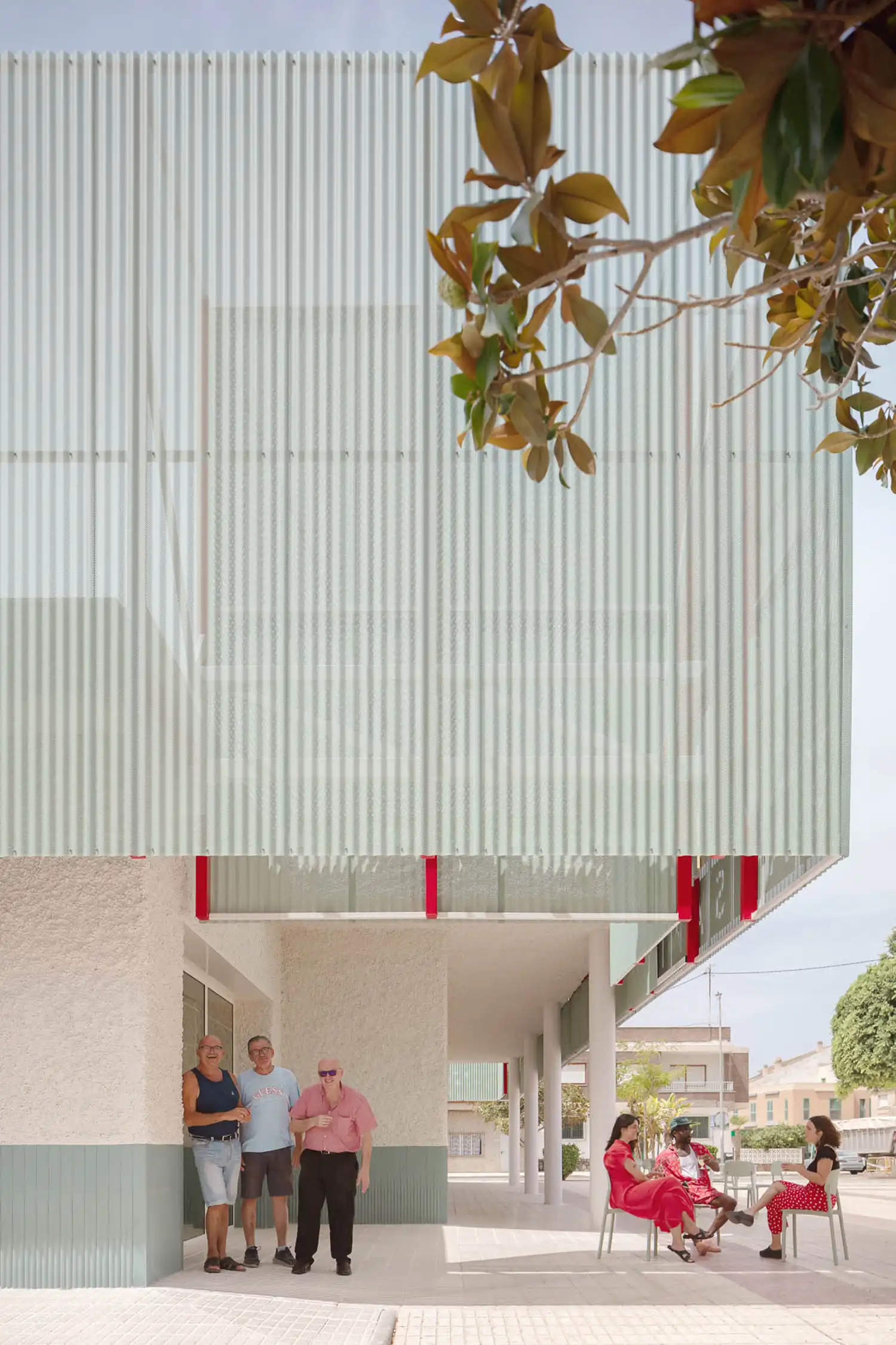 Close-up of the blue-green perforated metal skin and red structural accents designed by COR ARCHITECTURE+DESIGN.