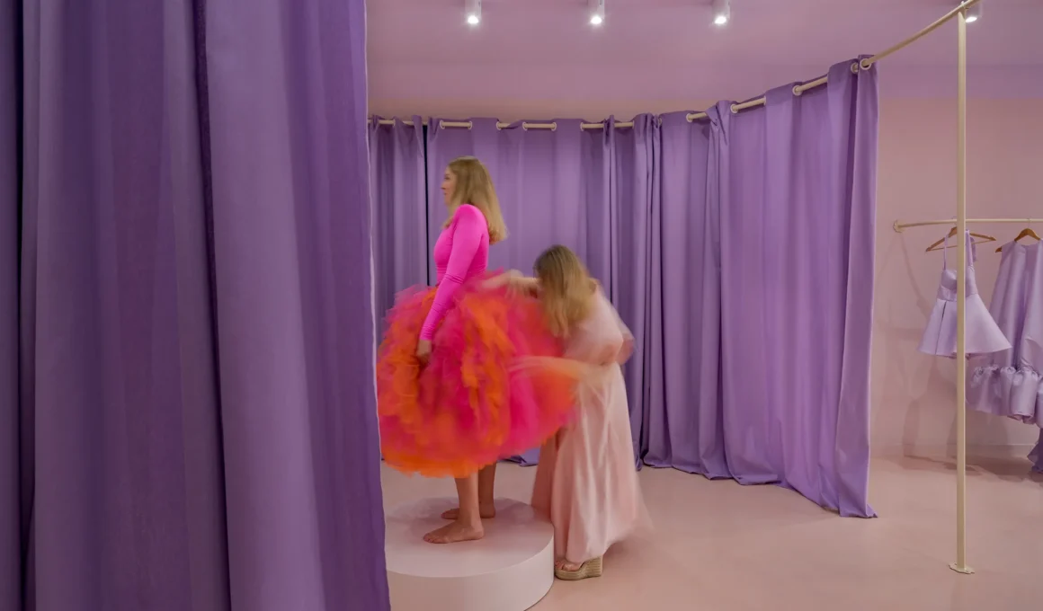 fitting a pink and orange dress on a platform