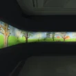 A wide-angle view of a curved dark gallery wall displaying David Hockney's illuminated digital landscape frieze.