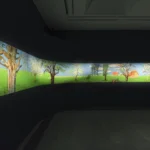 A wide-angle view of a curved dark gallery wall displaying David Hockney's illuminated digital landscape frieze.