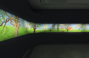 A wide-angle view of a curved dark gallery wall displaying David Hockney's illuminated digital landscape frieze.