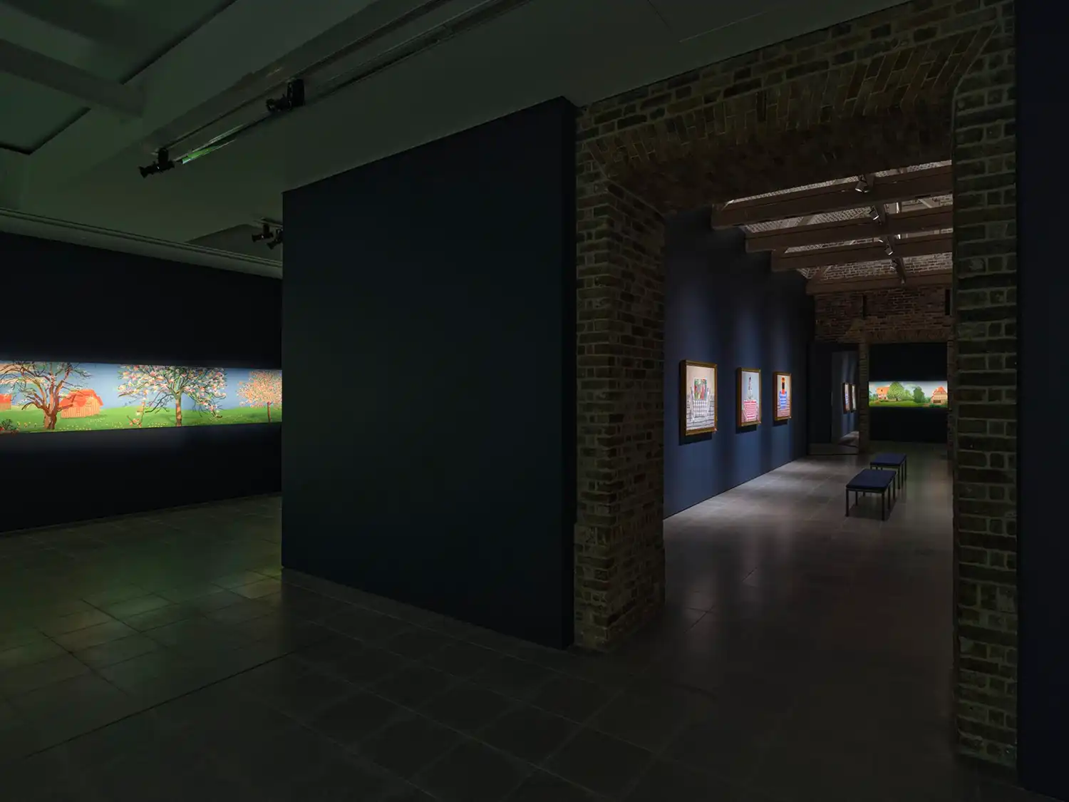 A view through a brick archway showing both the landscape frieze in one room and portrait paintings in another.