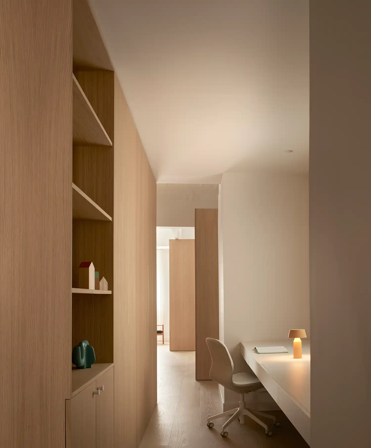 Integrated home office desk in a wide circulation area with oak shelving.