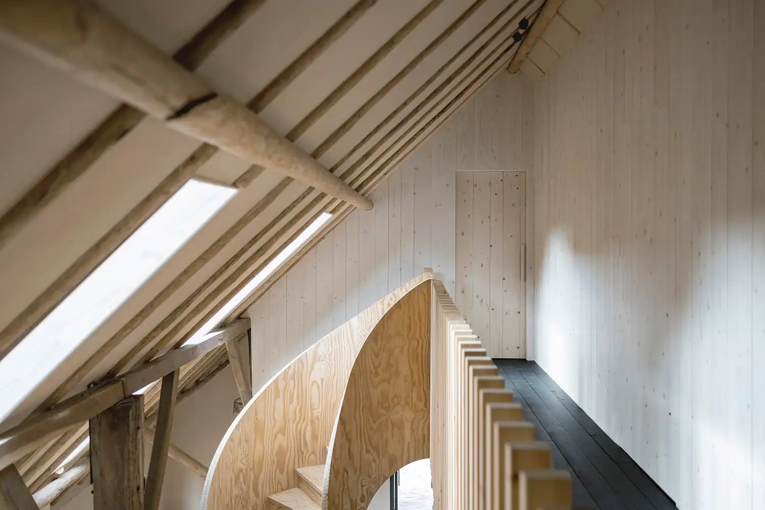Pine-clad upper hallway with a slatted timber balustrade and roof skylights.
