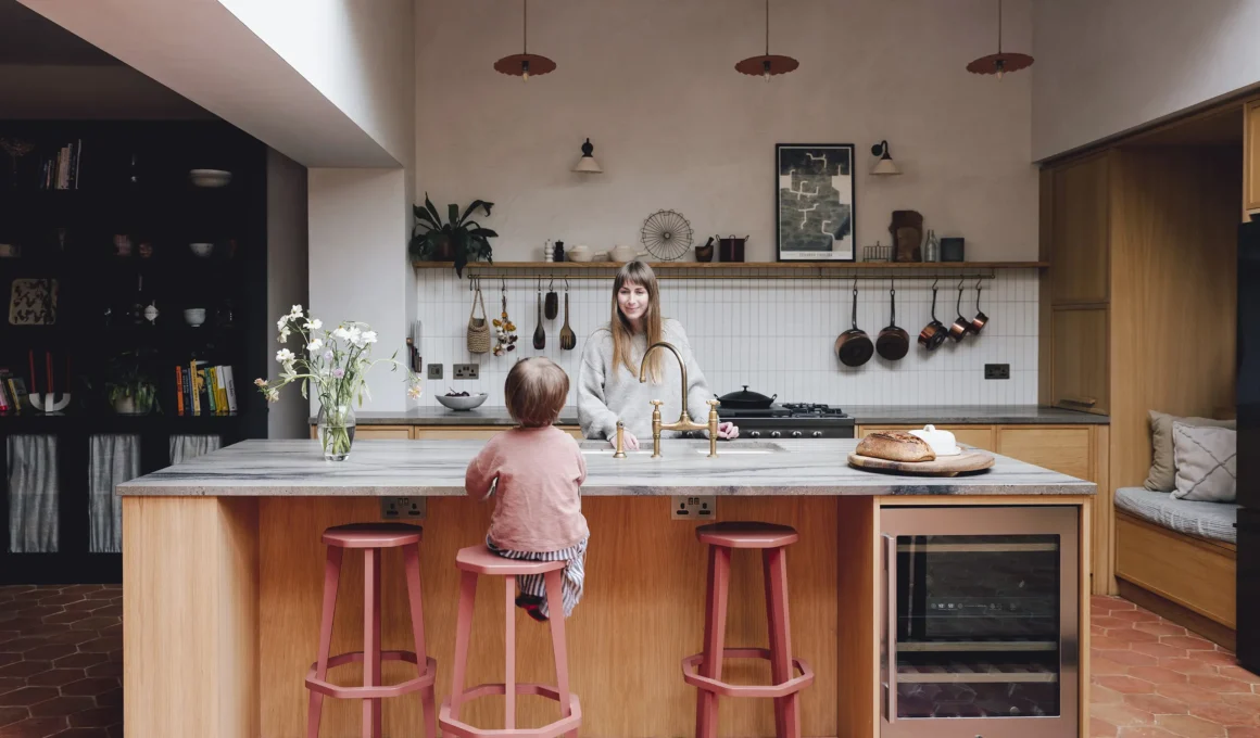 Modern kitchen with oak island, marble top, and hexagonal terracotta floor tiles.