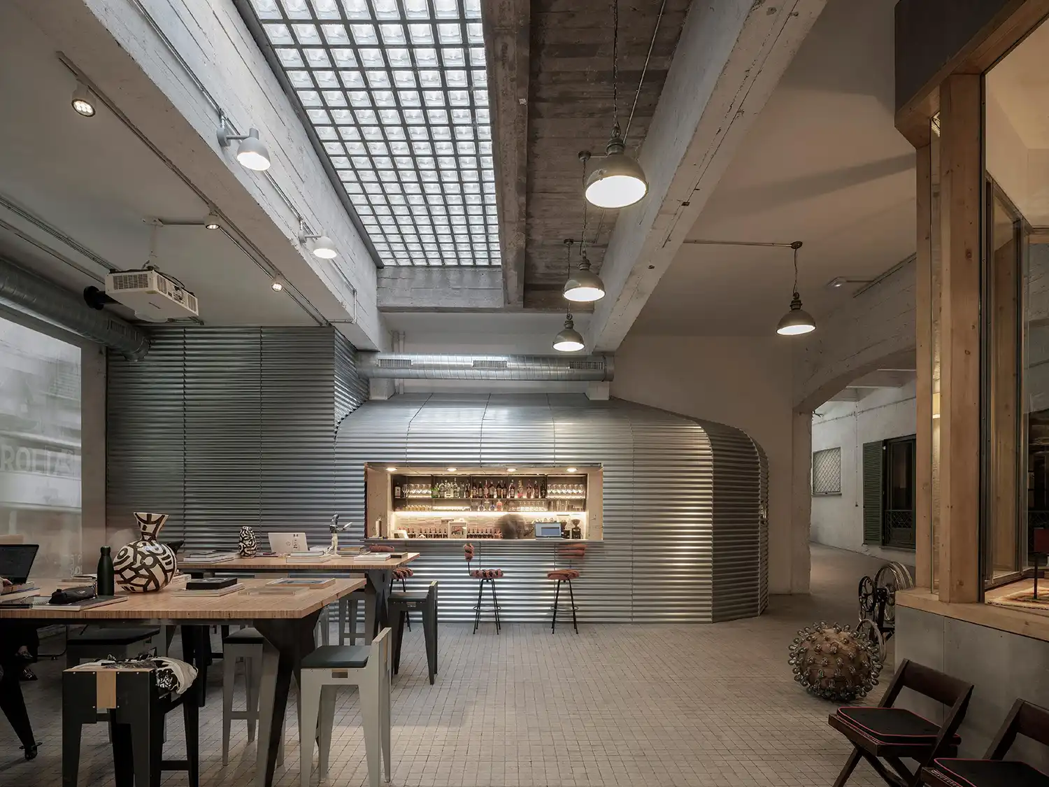 A bar and lounge area featuring a corrugated metal counter and industrial pendant lighting.