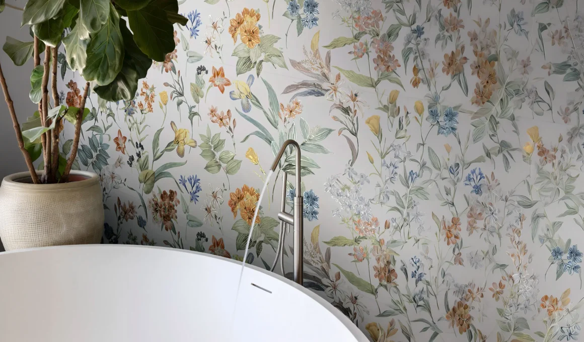 Modern bathroom interior with water flowing into a freestanding tub, featuring a large fiddle-leaf fig plant and detailed floral wallpaper with blue iris and orange flowers on a white background.