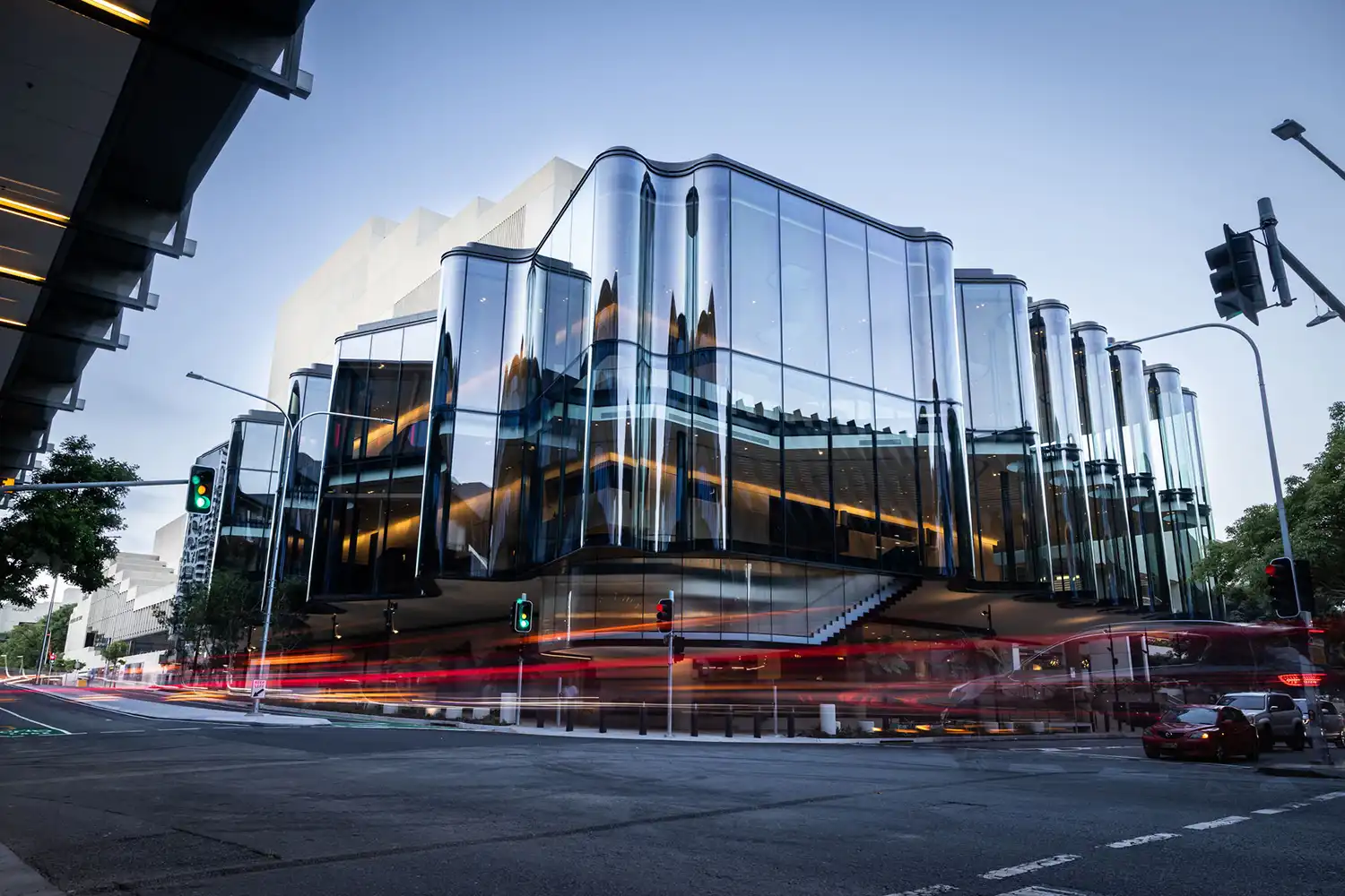Twilight long-exposure of the Glasshouse Theatre with vibrant light trails from passing cars.