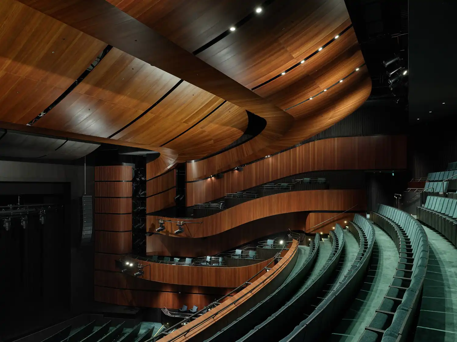 Wide interior of the 1,500-seat auditorium with dark timber ribbons and green seating.