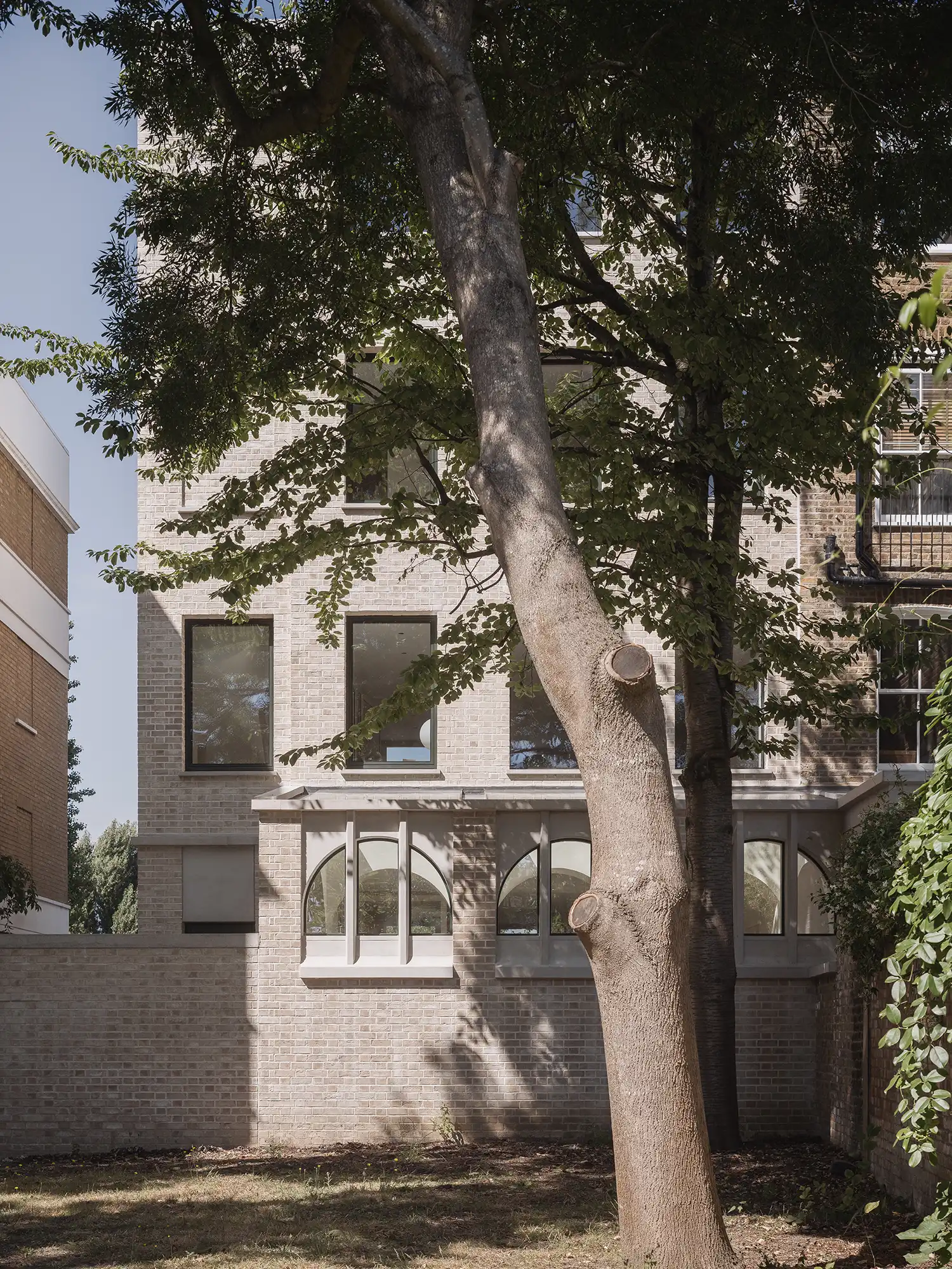 Rear facade of West London House extension with yellow brick and arched windows.