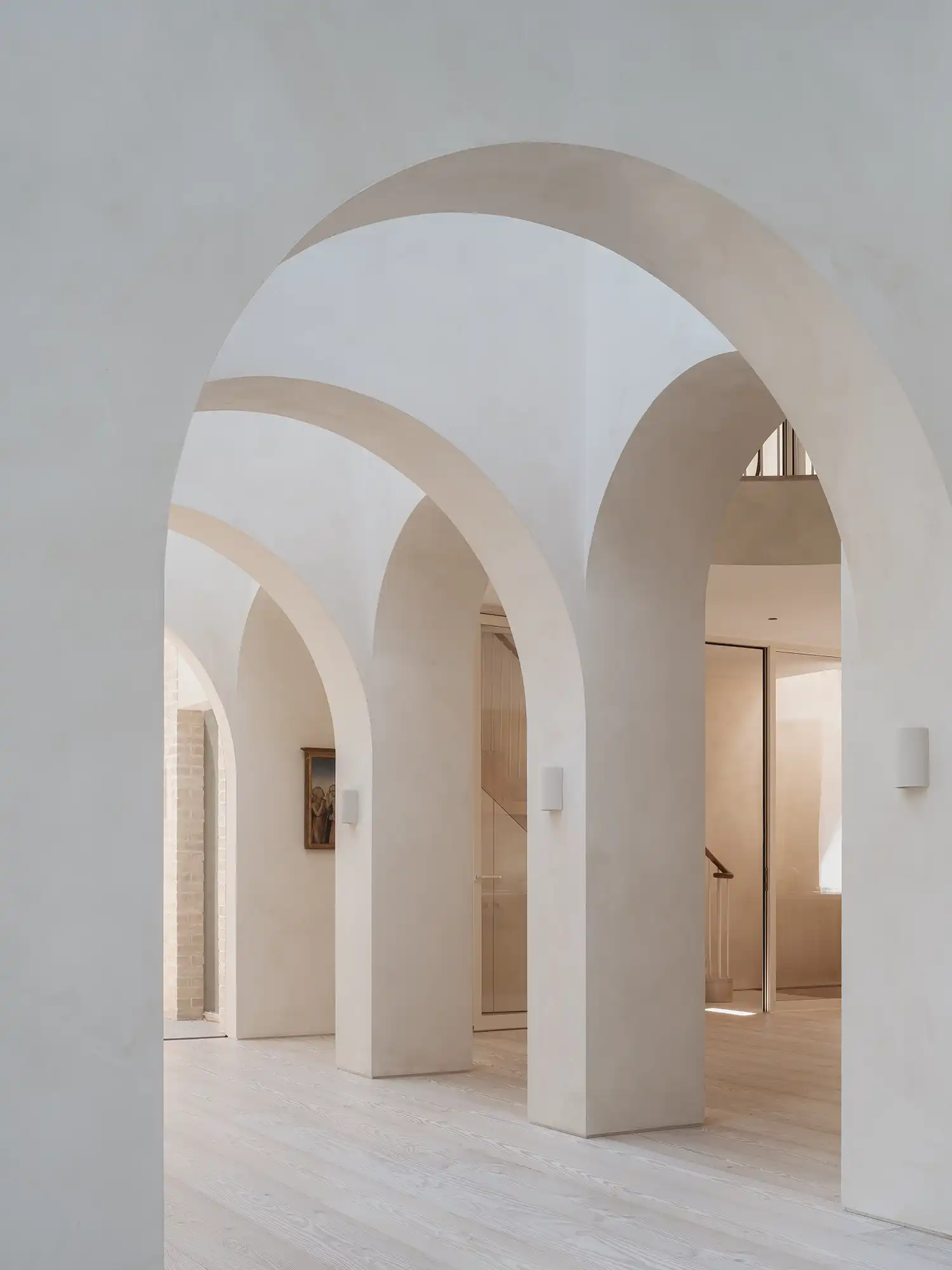 Minimalist white vaulted corridor with light-filled arches by Goldstein Heather.