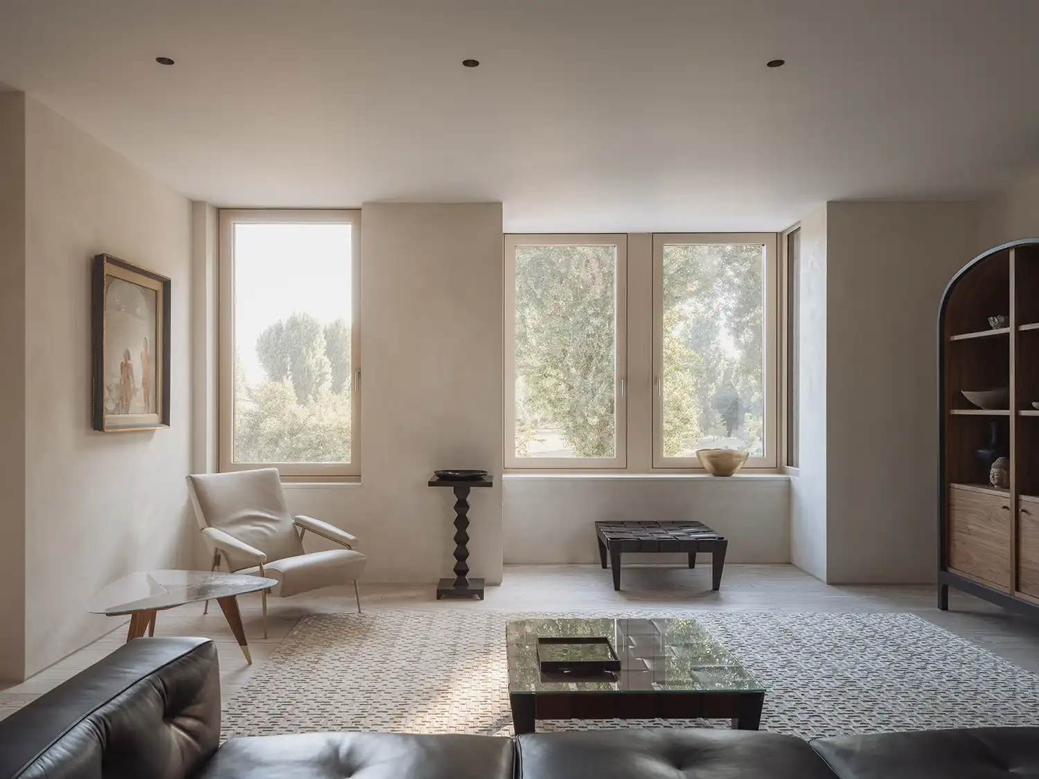 Sun-drenched minimalist lounge with large windows and contemporary furniture.