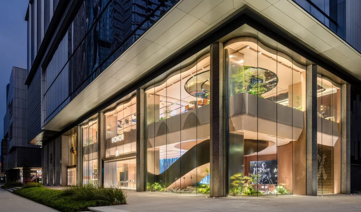 HONOR Flagship Store exterior featuring two-story curved glass facade and illuminated interior at dusk