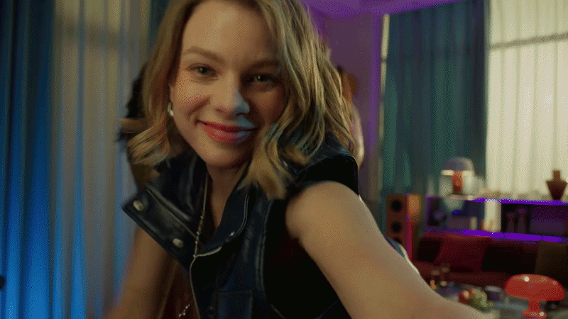 A young woman smiling and dancing while holding a smartphone that is autonomously tracking her movement.