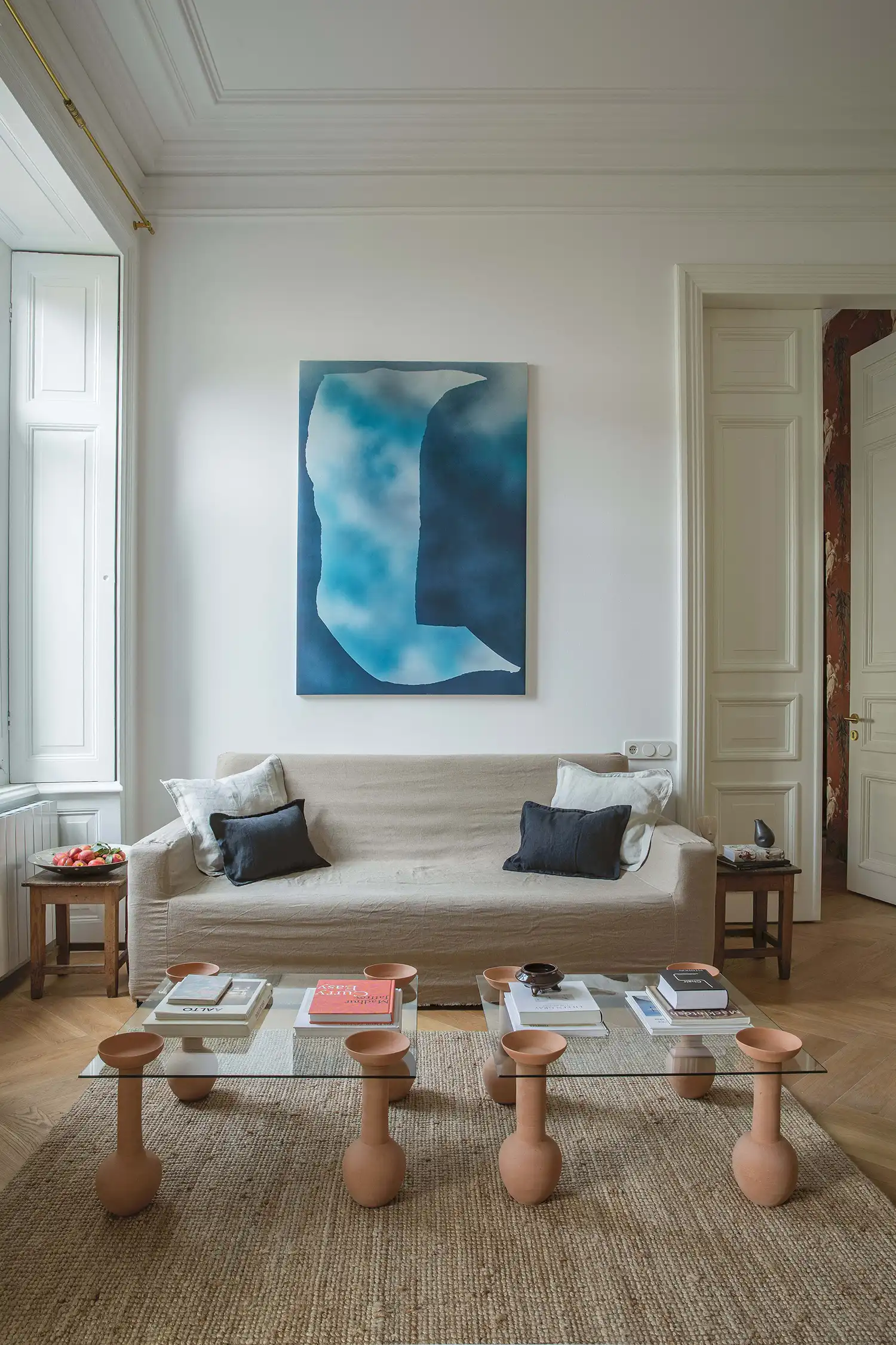 PIALA Coffee Table in a high-ceilinged living room with blue abstract art.