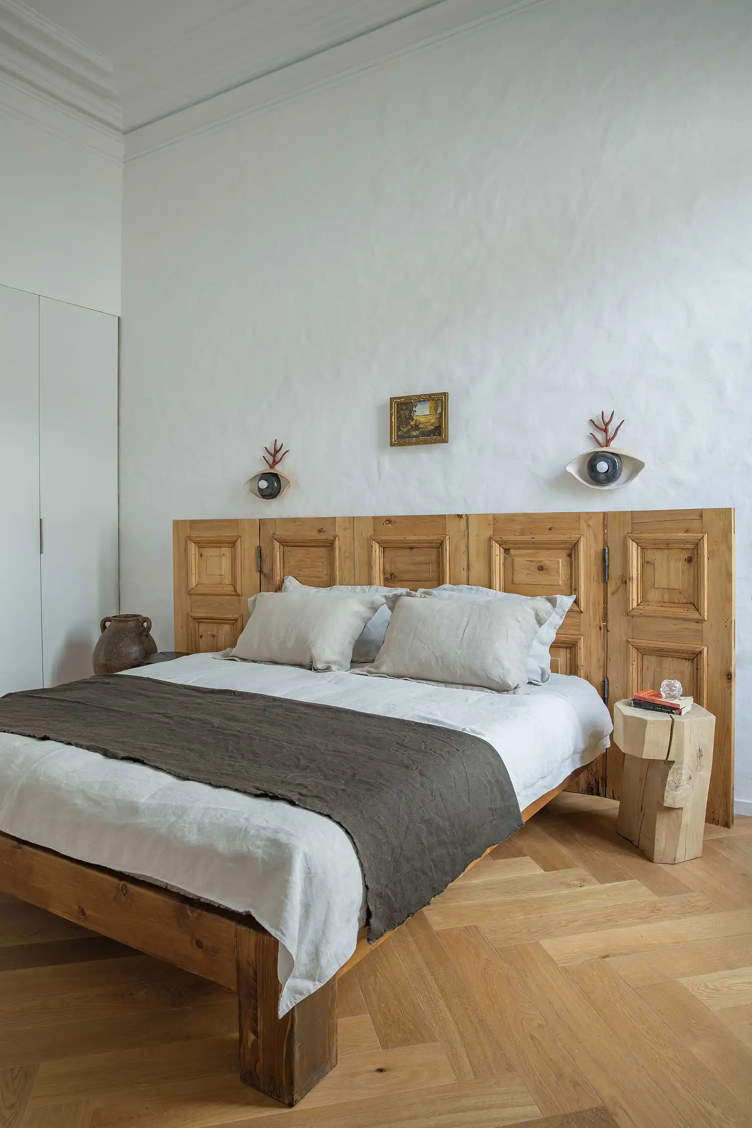 Guest bedroom with custom wooden headboard and neutral linen bedding.