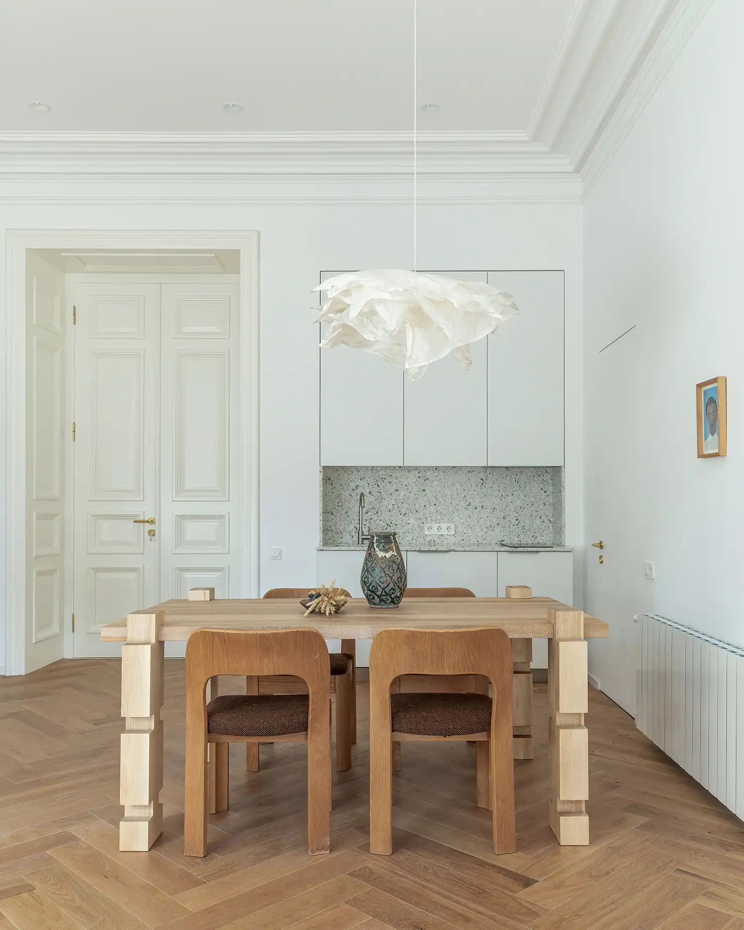 Open-plan dining and kitchen area with white cabinetry and oak flooring.