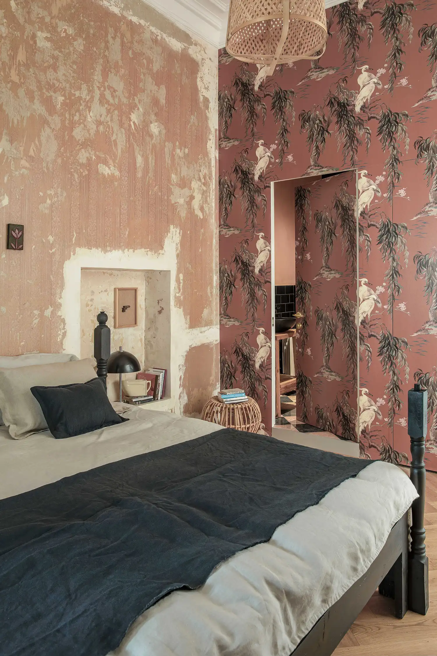 Hidden bathroom door concealed by floral wallpaper in an orange bedroom.