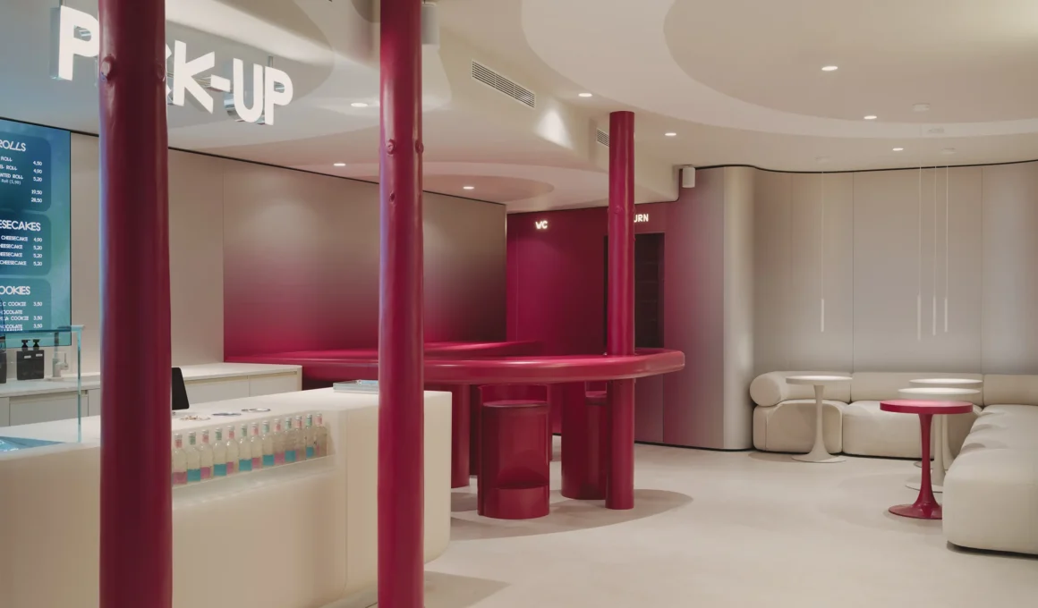 Wide view of Cinnamood Barcelona interior featuring deep pink structural columns and a white curved service counter.