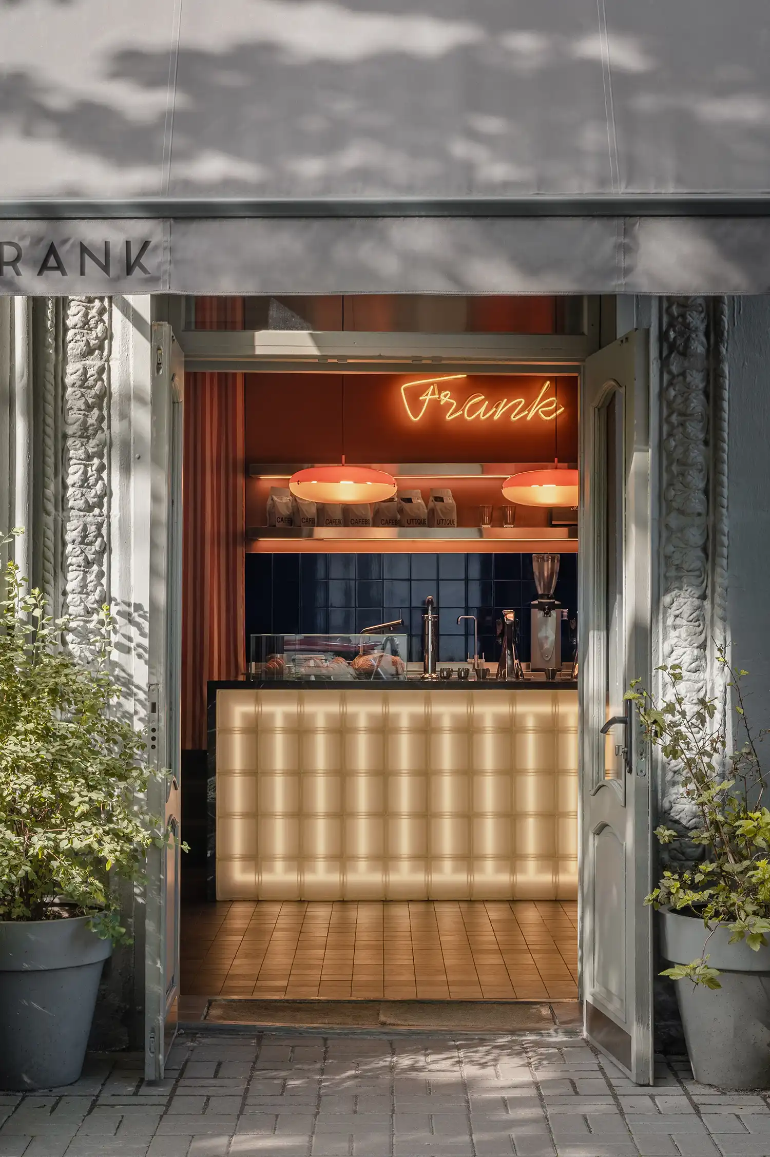 Exterior view of Frank cafe entrance in Kyiv with open doors and grey awning.