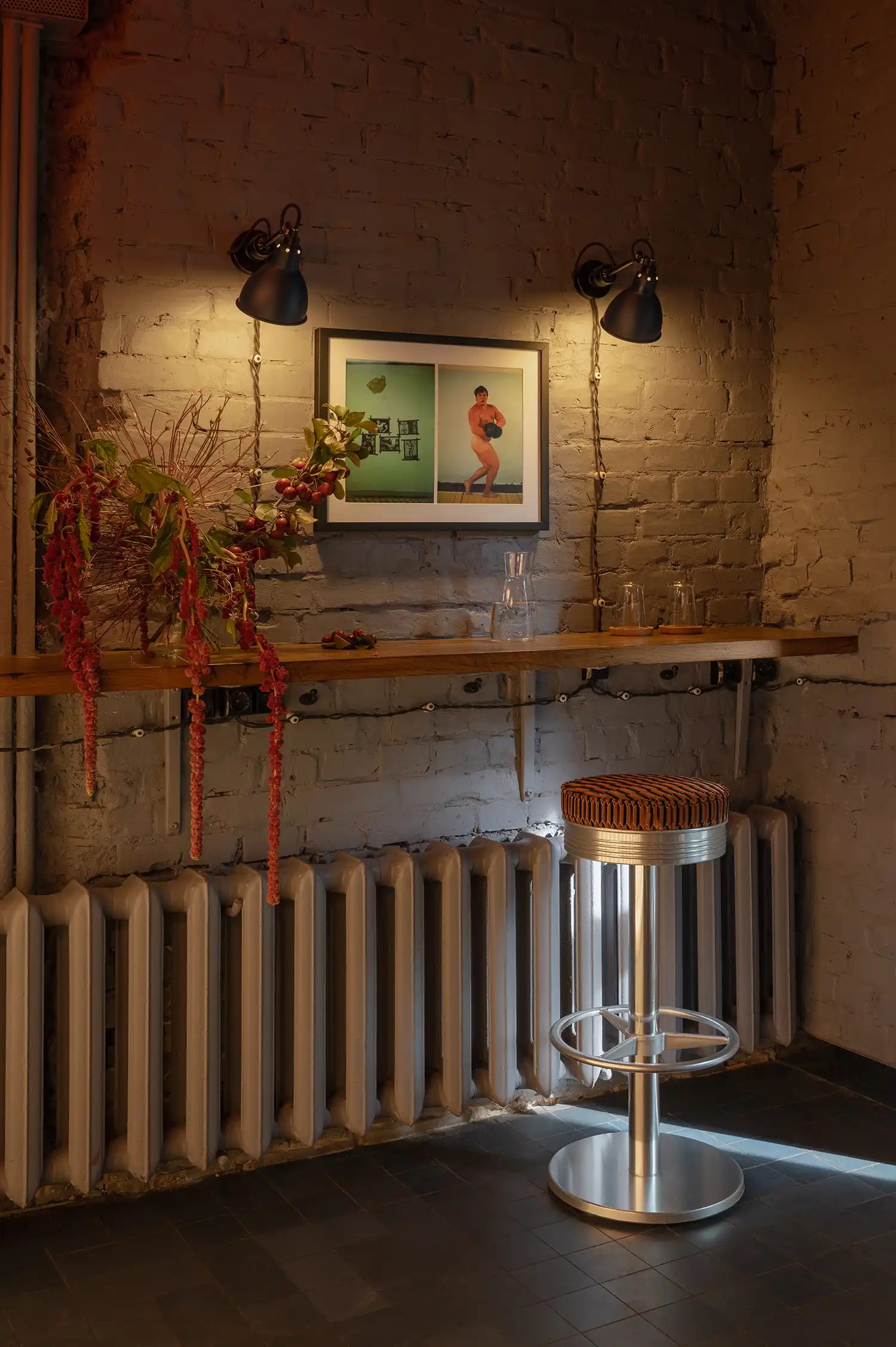 Wooden bar counter along a grey brick wall with radiator and Lampe Gras lighting.