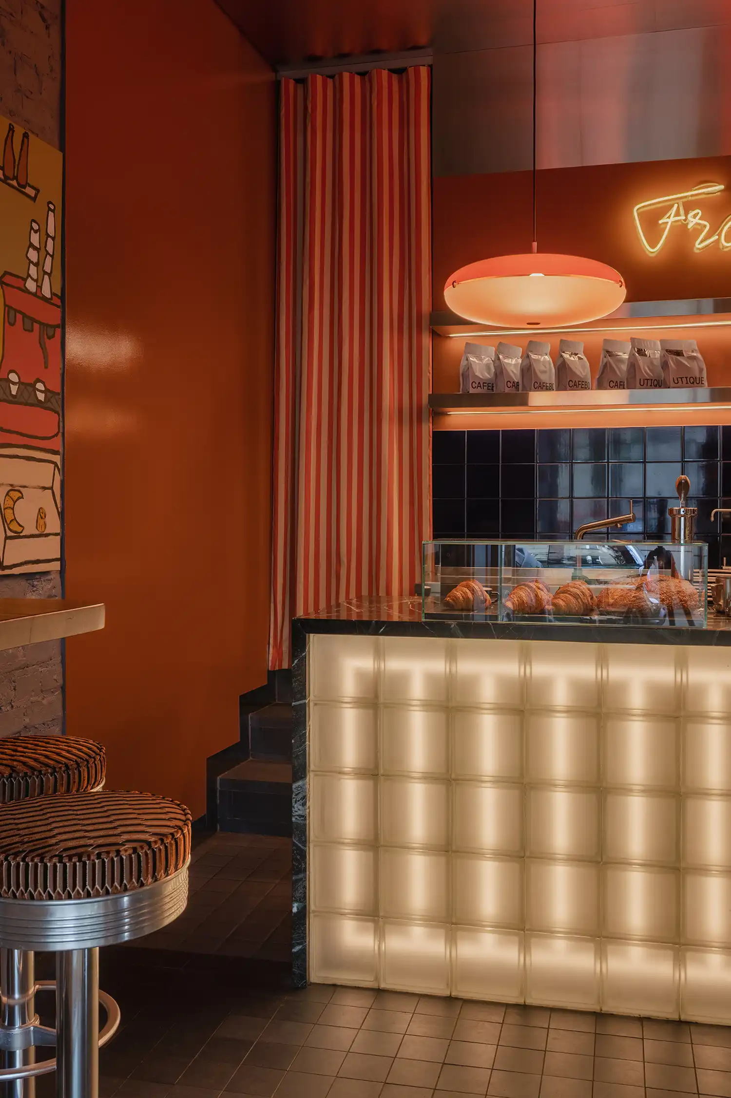Close-up of the glass block bar counter with pastries and a striped textile curtain.